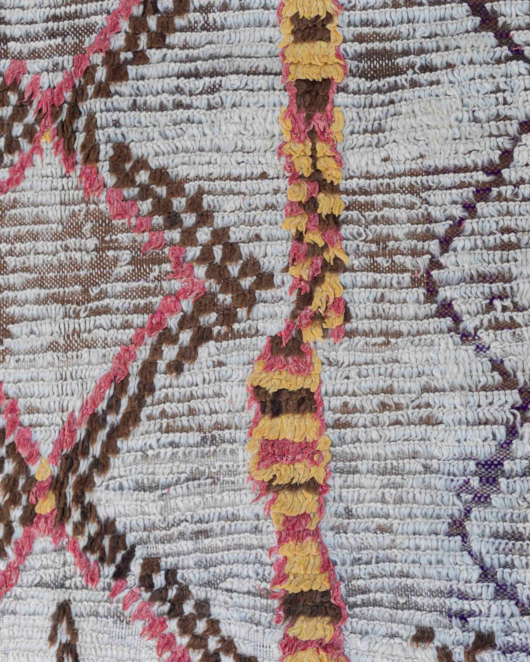 Dettaglio dei rombi e dei disegni della passatoia Azilal vintage con fondo sfumato grigio-marrone e motivi tribali rosso-rosa, ocra, marrone