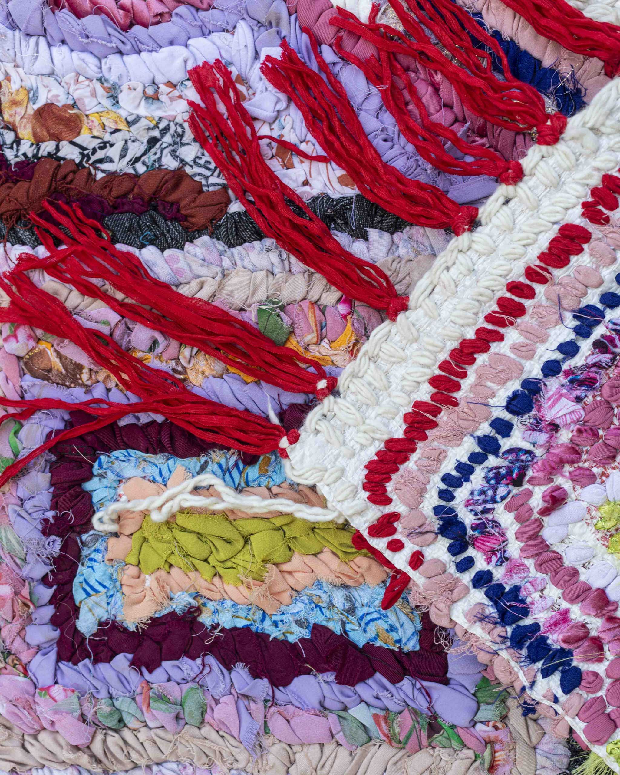 Dettaglio dritto e rovescio del tappetino in strisce tessili annodate a mano, con frange rosse