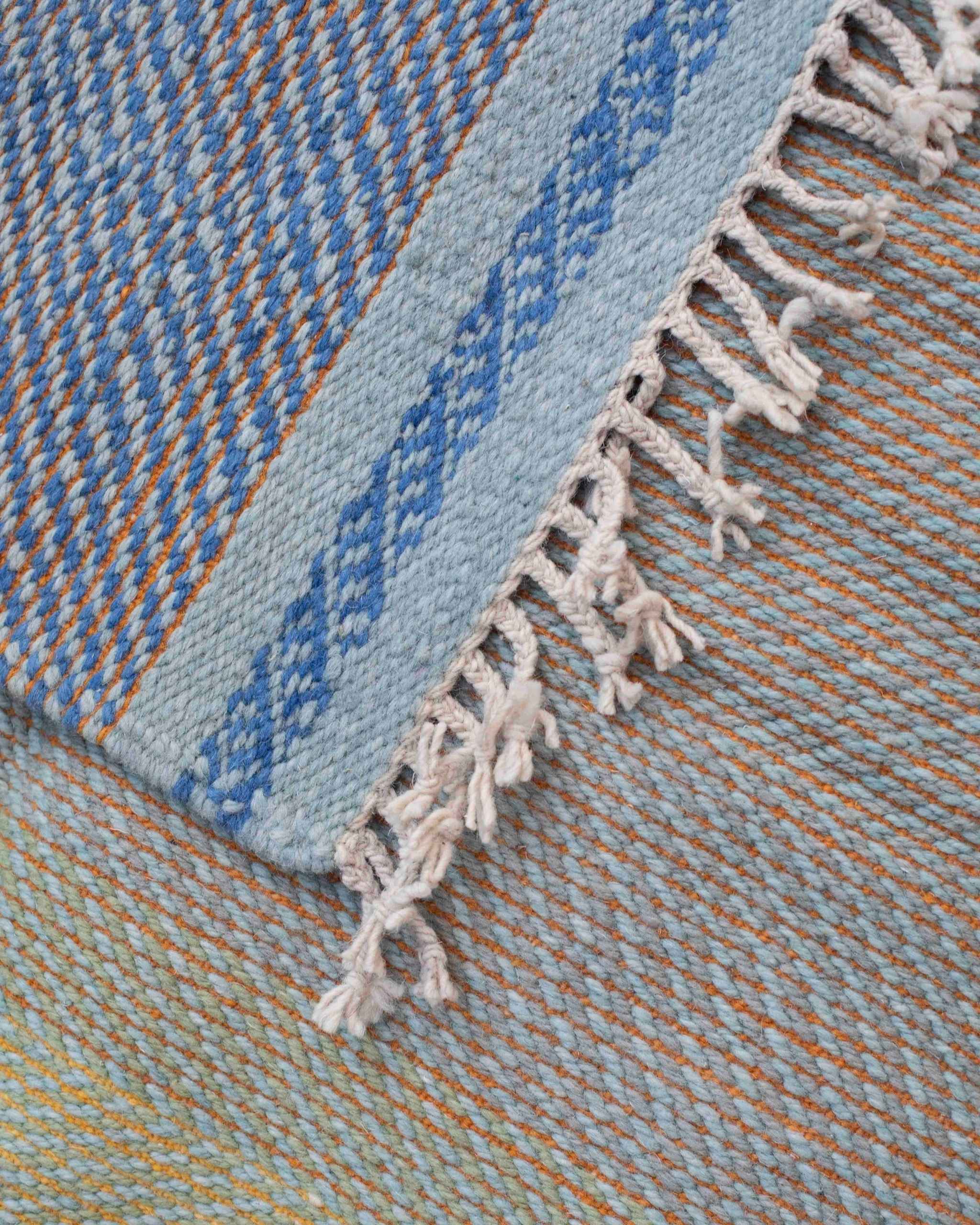 Dettaglio del tappeto fronte e retro in lana con trama azzurra, blu, giallo oro e arancione