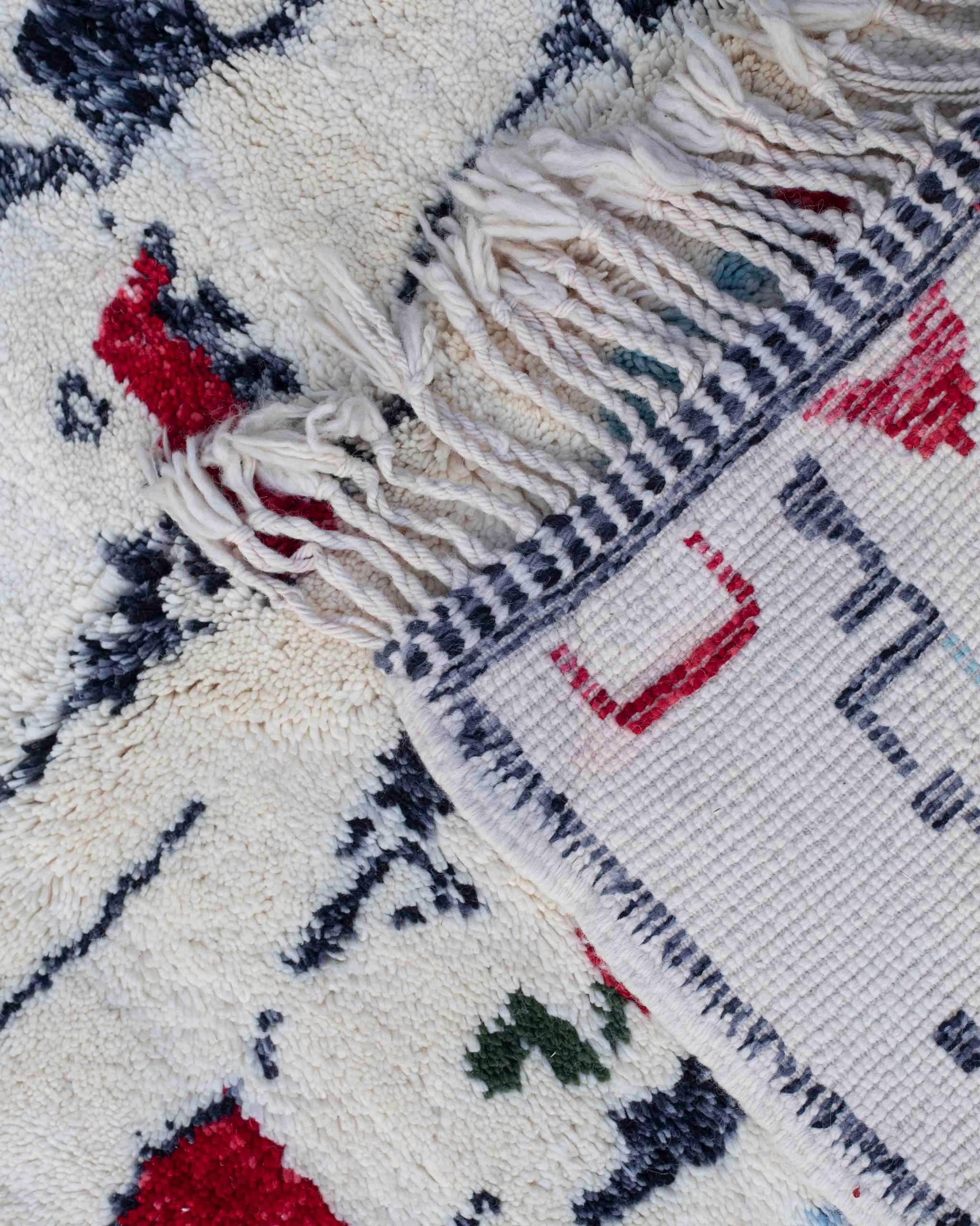 Dettaglio fronte retro del tappeto Beni Mrirt in lana bianca con figure astratte nere e rosse