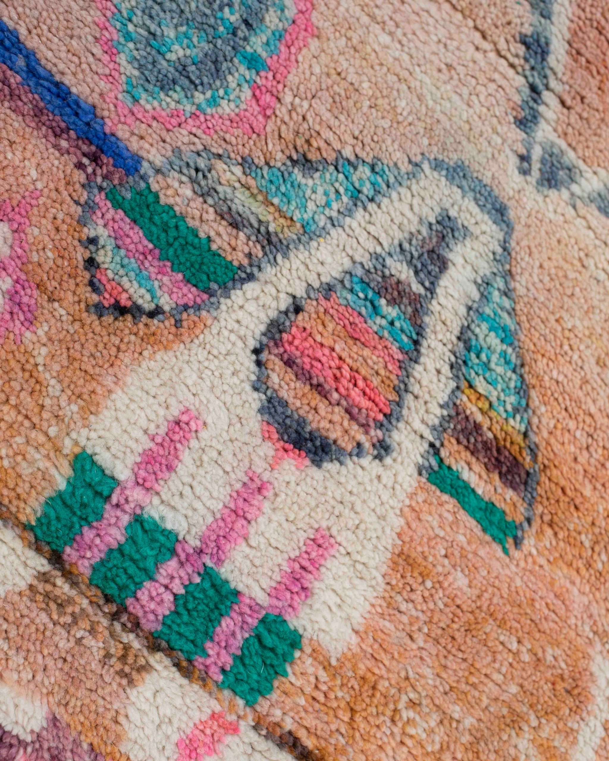 Dettaglio della lana e di un disegno che ricorda un vaso o un oggetto domestico stilizzato sul tappeto berbero Beni Ourain multicolore