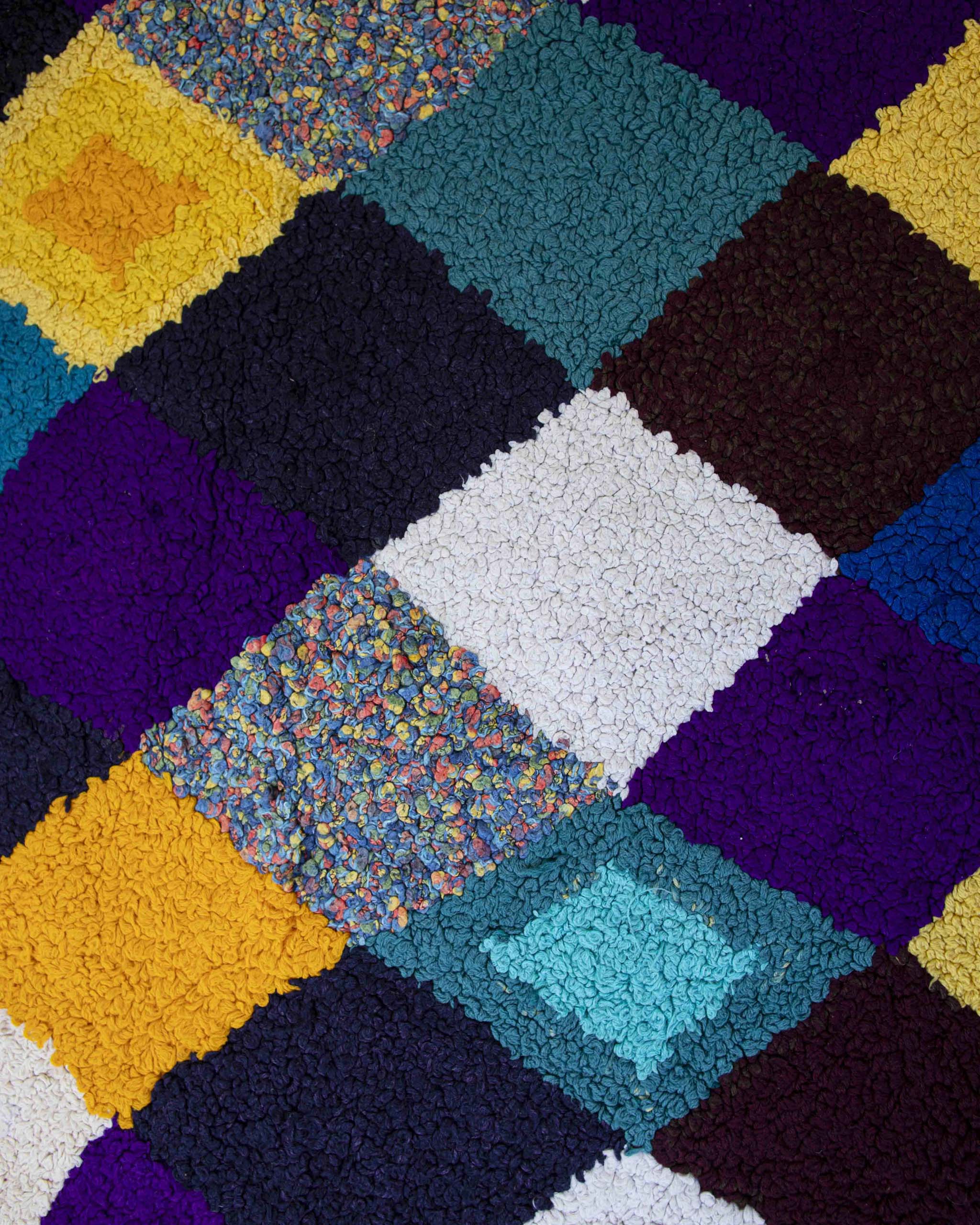 Dettaglio del tappeto Zindekh in tessuti riciclati lavorati a punch needle con motivo argyle di rombi multicolore
