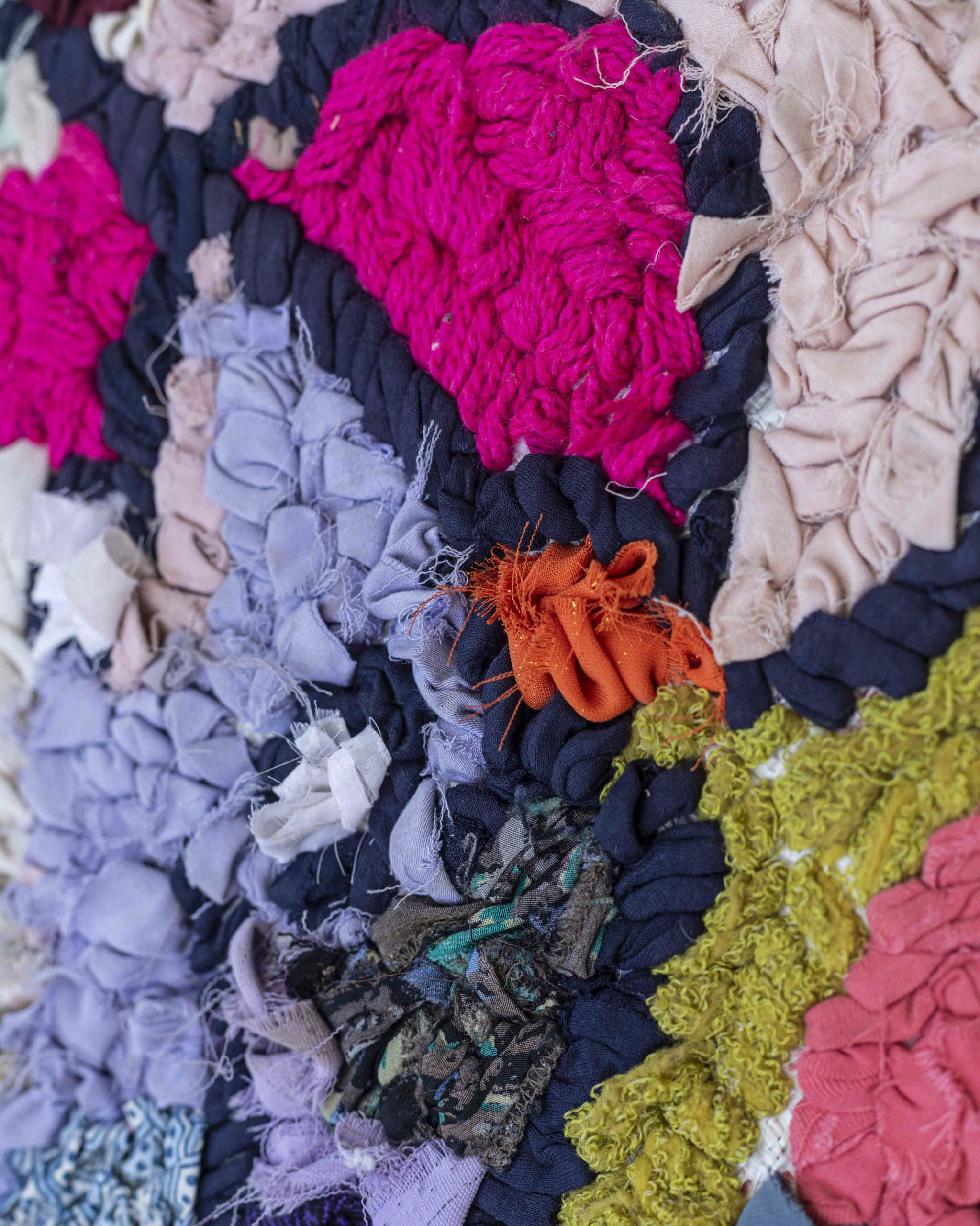 Dettaglio dei tessuti misti utilizzati per realizzare il tappetino-arazzo nei colori fucsia, lilla, giallo, rosa, grigio