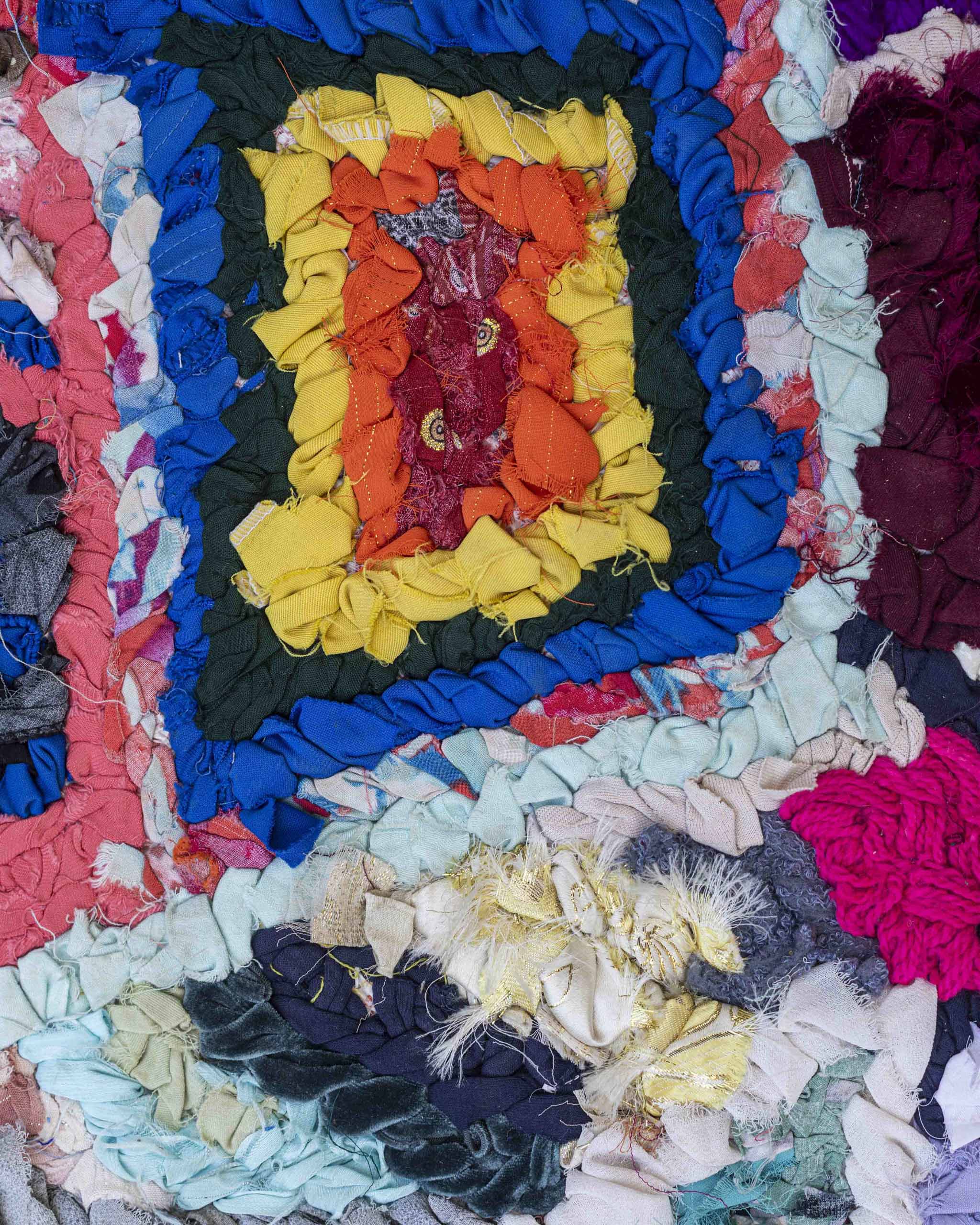 Dettaglio del tappetino arazzo in trisce di stoffe riciclate in colori bold fluo, qui blu, giallo, arancione, rosso, azzurro, grigio