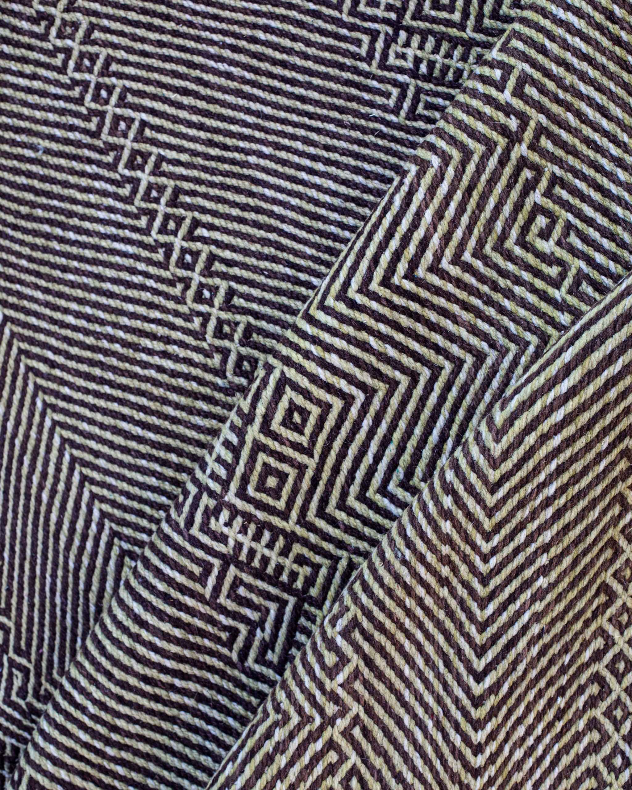 Dettaglio della trama del tappeto Zanafi con micro pattern labirintici e linee a spina di pesce bianchi-neri