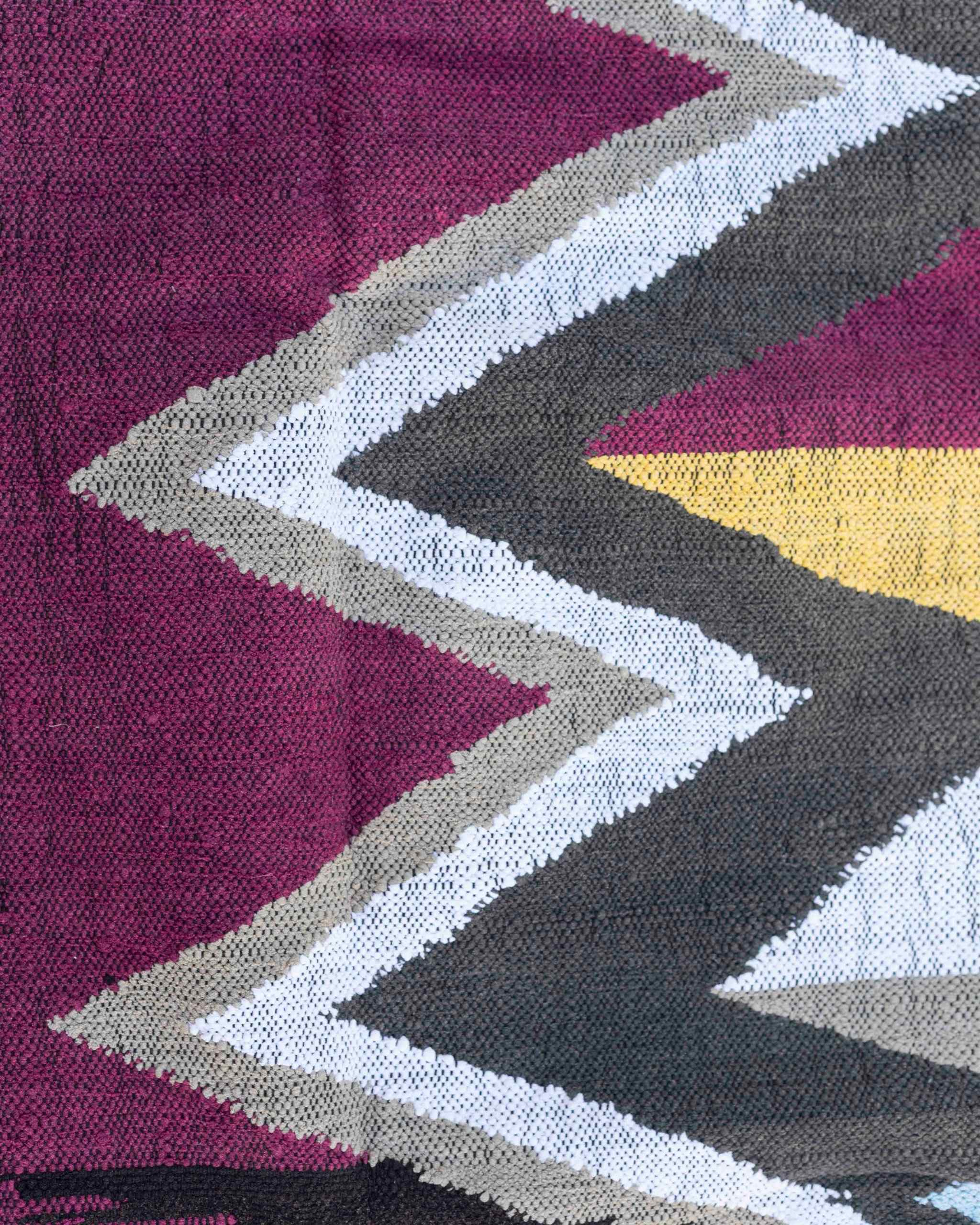 Dettaglio del grande motivo a zigzag del tappeto boucherouite con viola-magenta, grigio, bianco e giallo ocra
