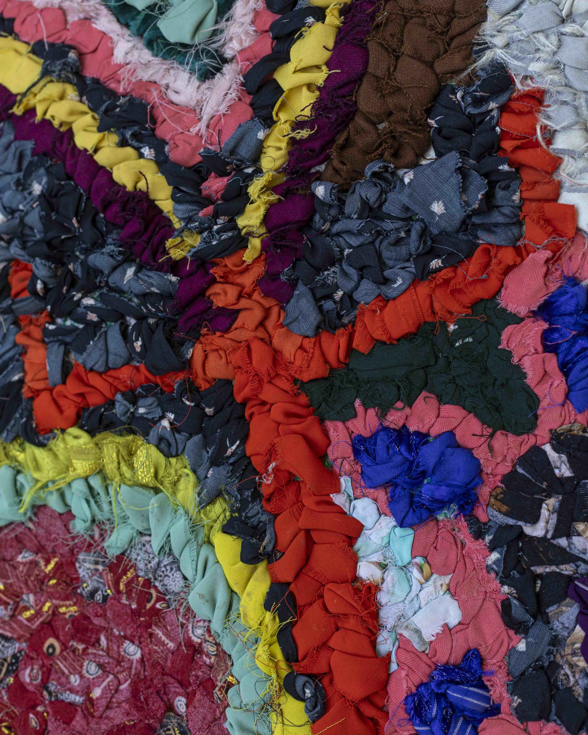 Dettaglio Zindekh annodato a mano in tessuti di riciclo con simbolo ⵣ Yaz rosso e segni tribali totemici multicolore