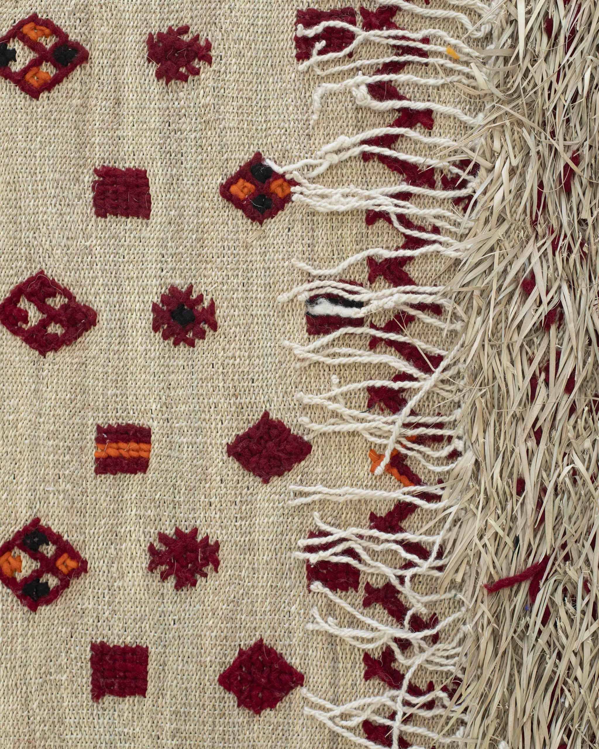 Dettaglio del dritto del tappeto con simboli e rovescio con paglia a vista