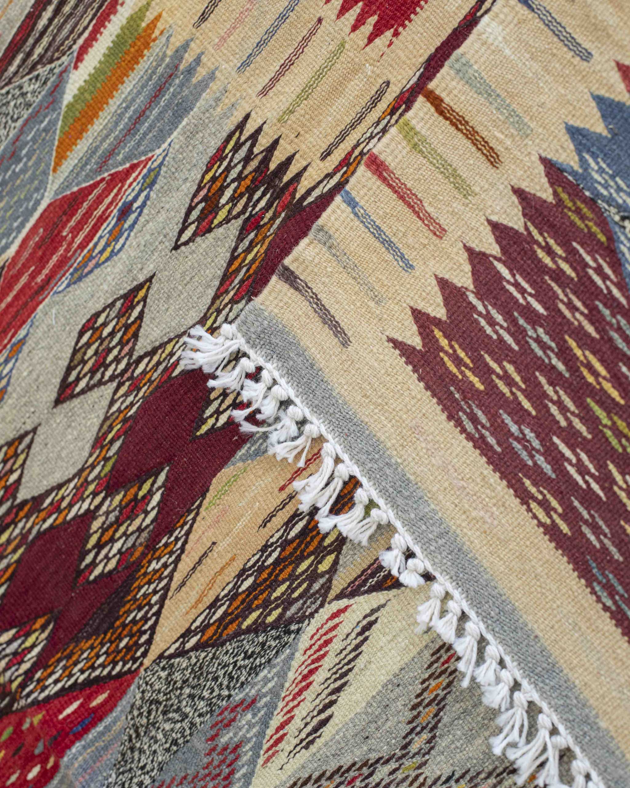 Dettaglio frange corte bianche su tappeto in lana a tessitura piatta colorato