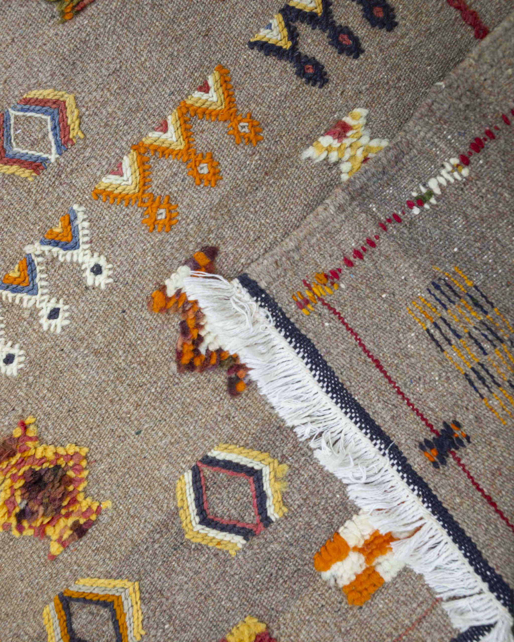 Dettaglio dritto e rovescio della passatoia kilim a fondo beige con decori berberi colorati