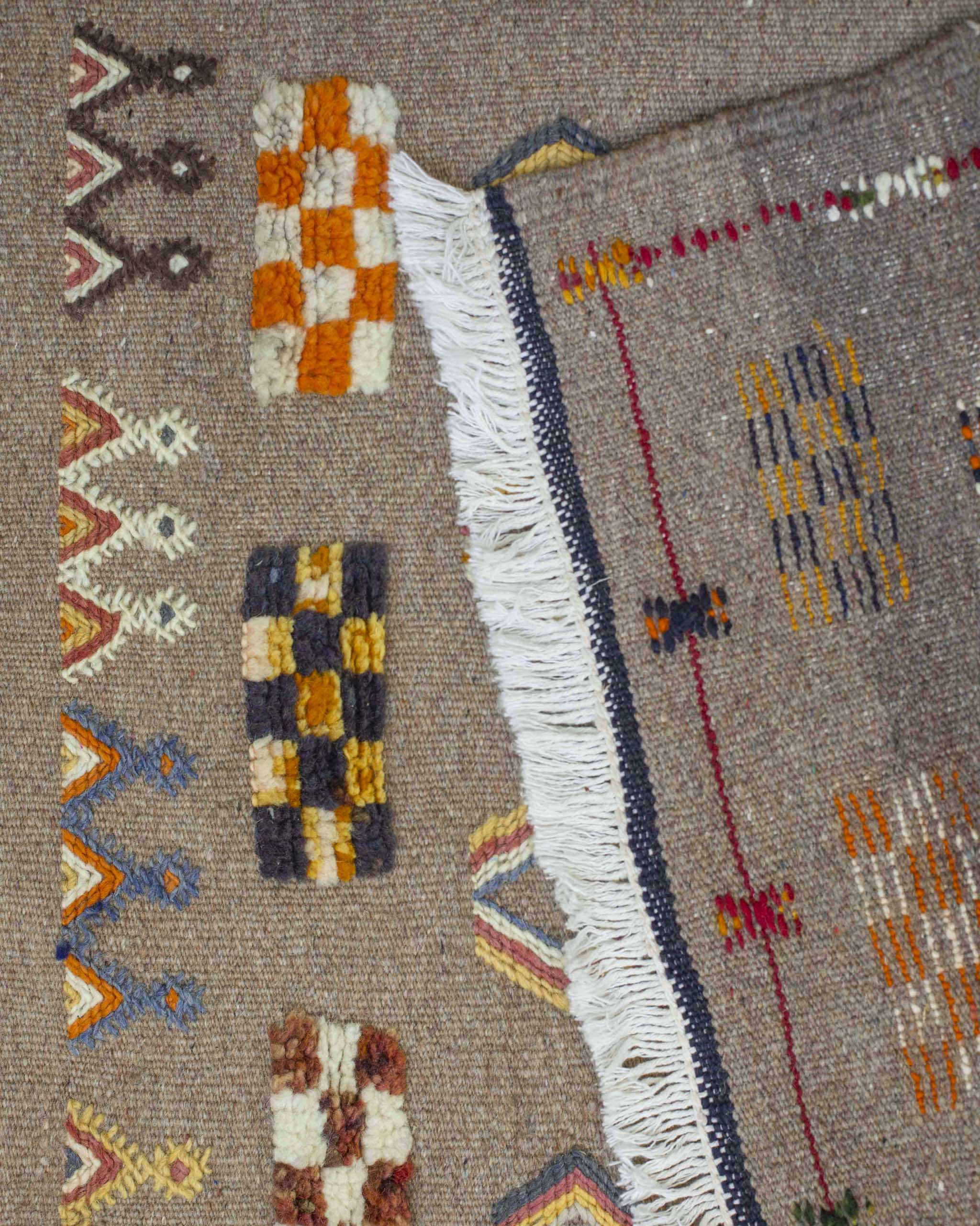 Dettaglio della passatoia beige con decori fronte e retro con frange bianche