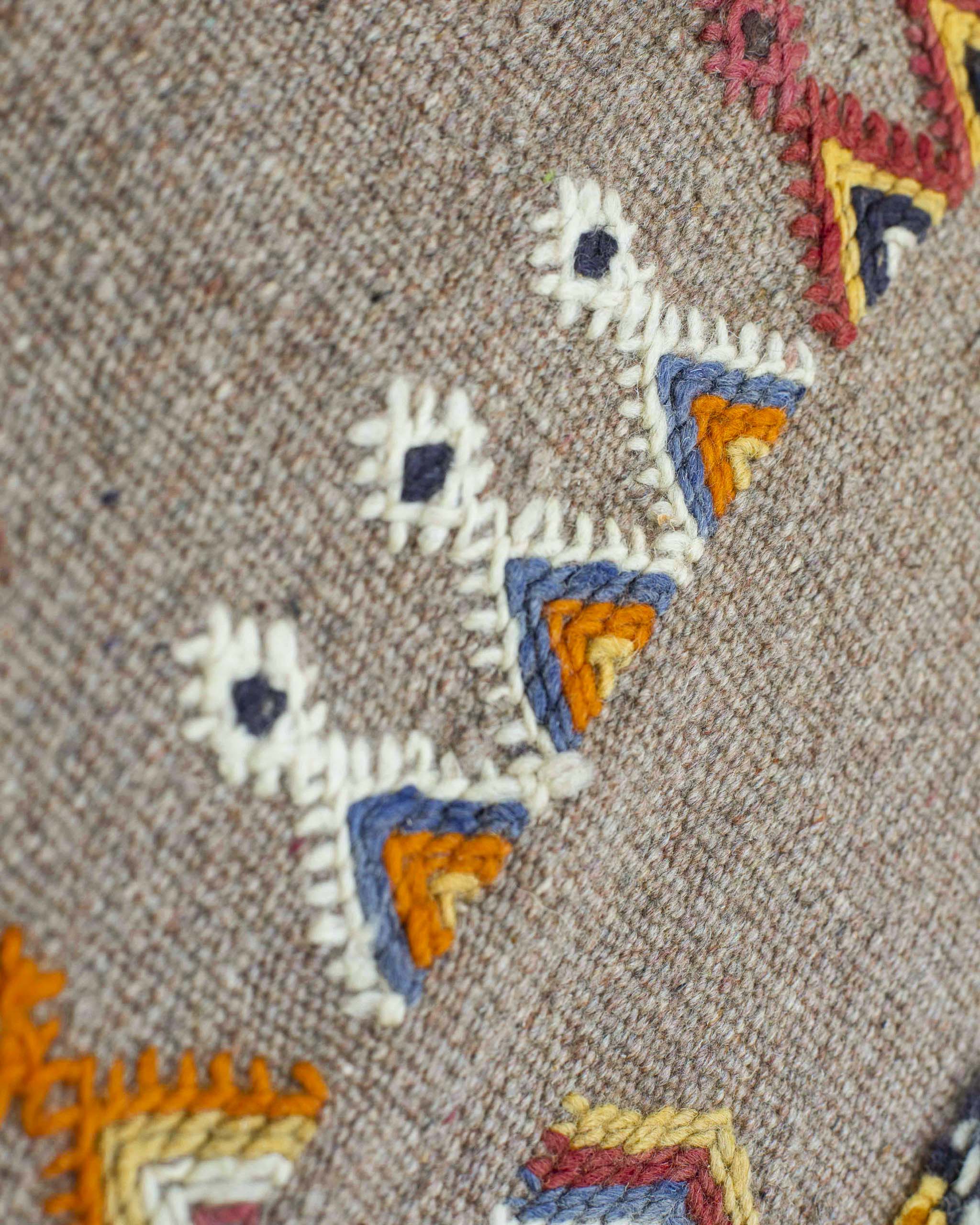 Dettaglio di alcuni simboli berberi a triangolo ricamati sulla passatoia kilim beige