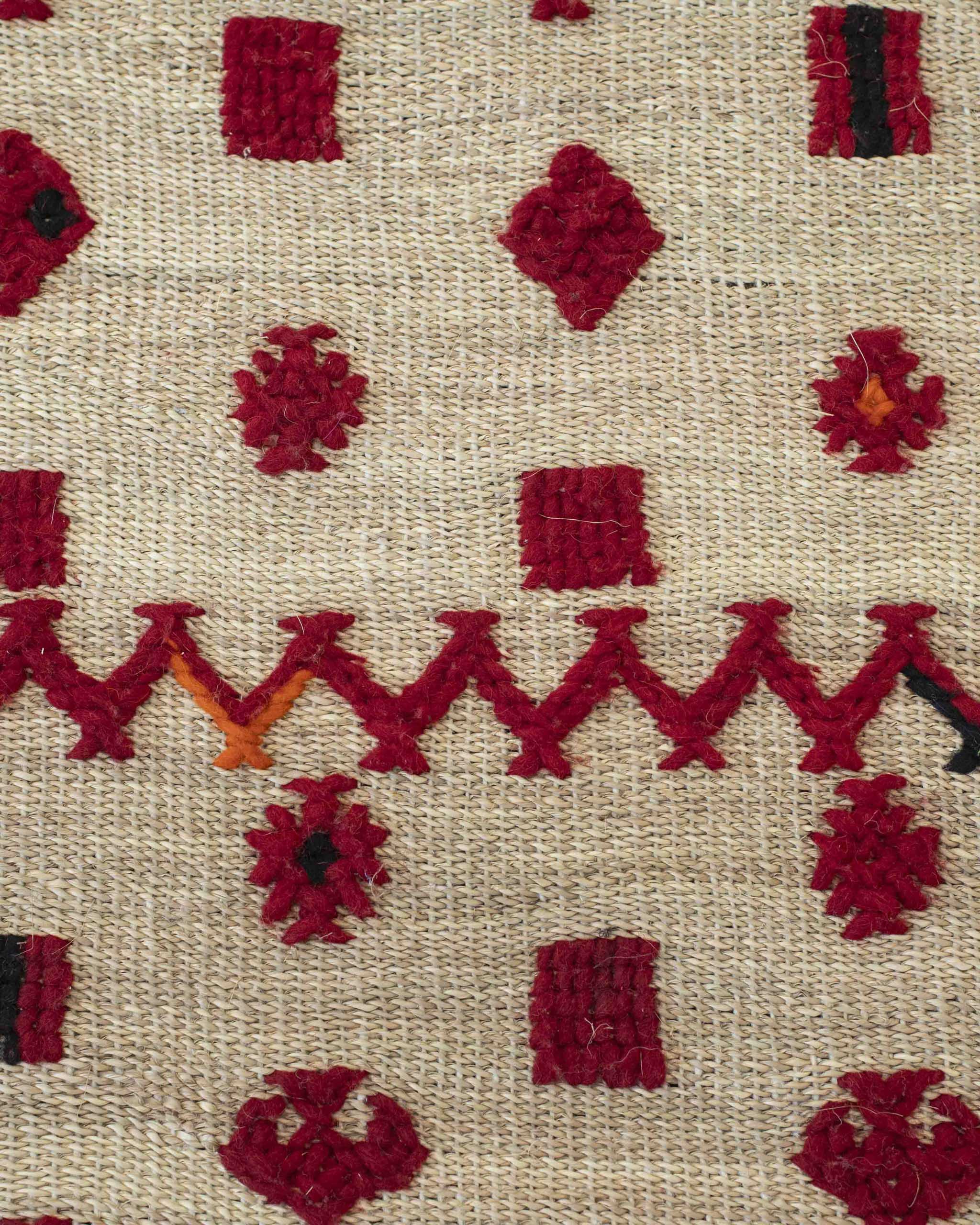 Dettaglio della superficie del tappeto in paglia intrecciata fitta con decorazioni tessili a zigzag e geometrici