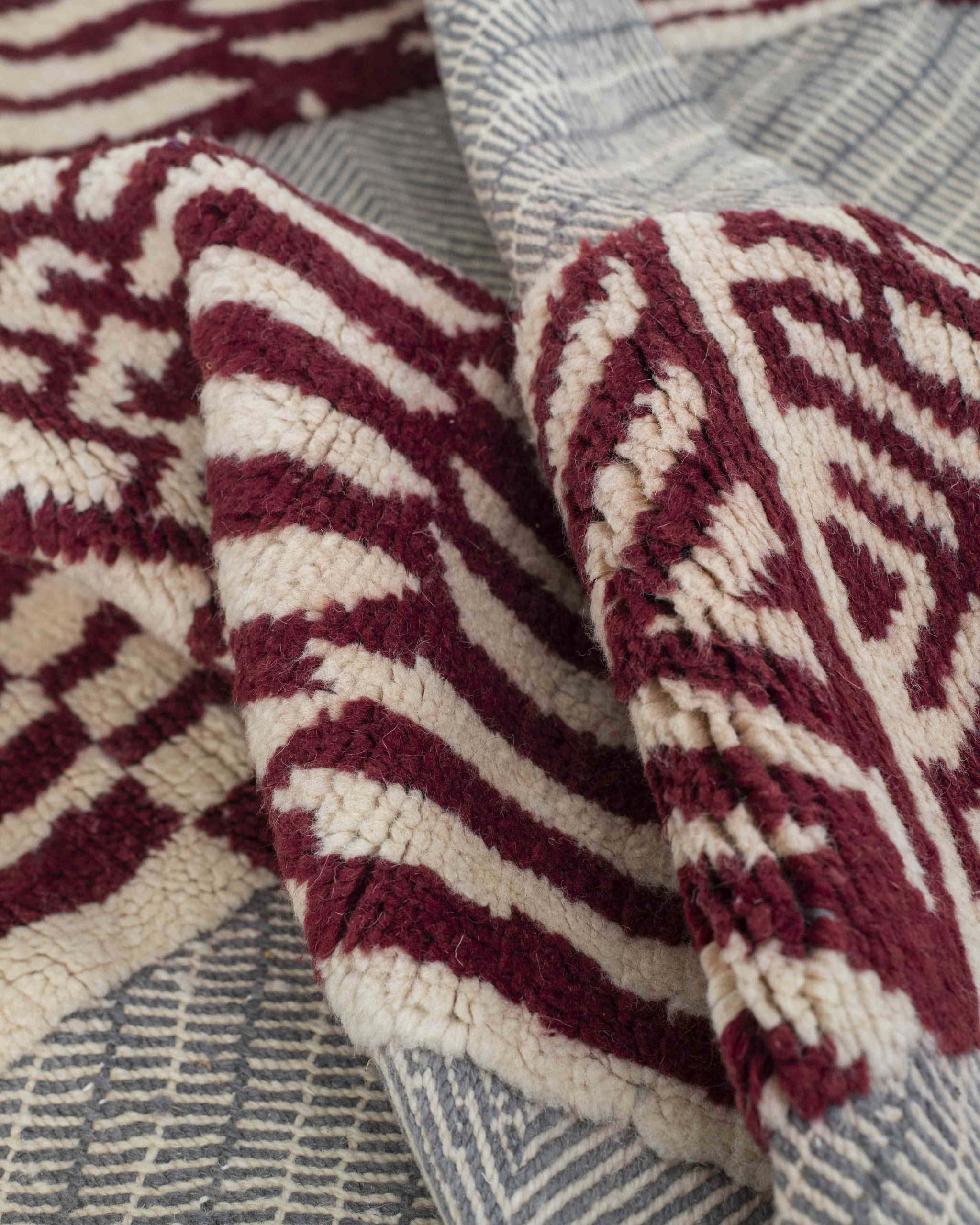 Dettaglio del tappeto con campo a tessitura piatta grigio-azzurro e sezioni a vello corto rosso-bianche