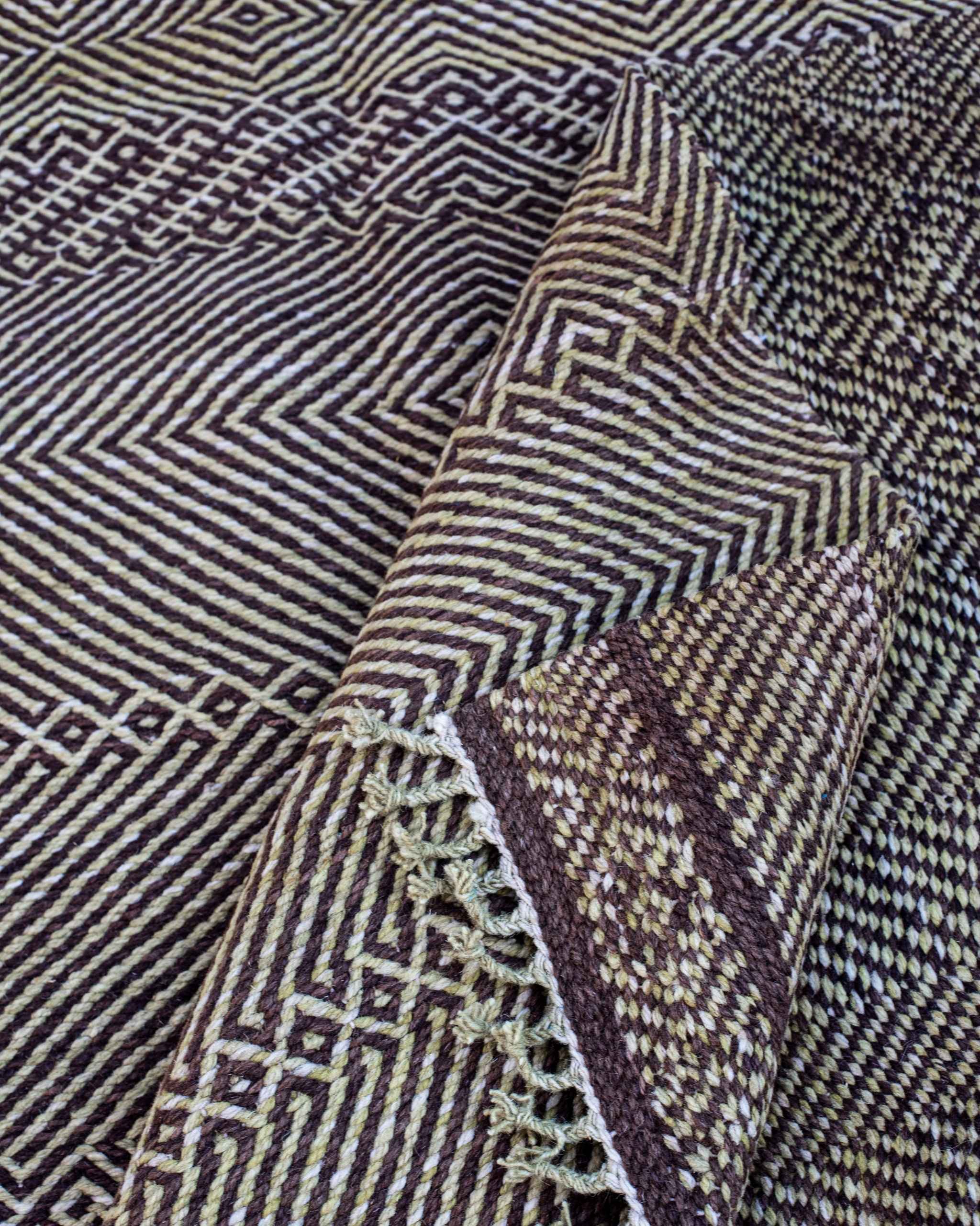 Pieghe del tappeto Zanafi che mostrano fronte e retro a tessitura piatta con rombi e zigzag bianchi e neri