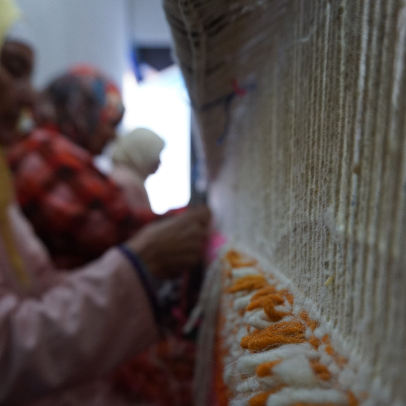 Moroccan artisans weaving traditional carpet on ancient loom, showcasing the art of Moroccan rug making