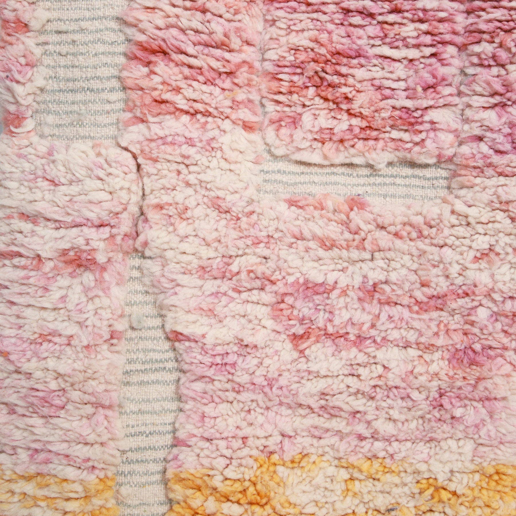 dettaglio della lana annodata color rosa sfumato e degli intrecci chiari di una passatoia beni ourain