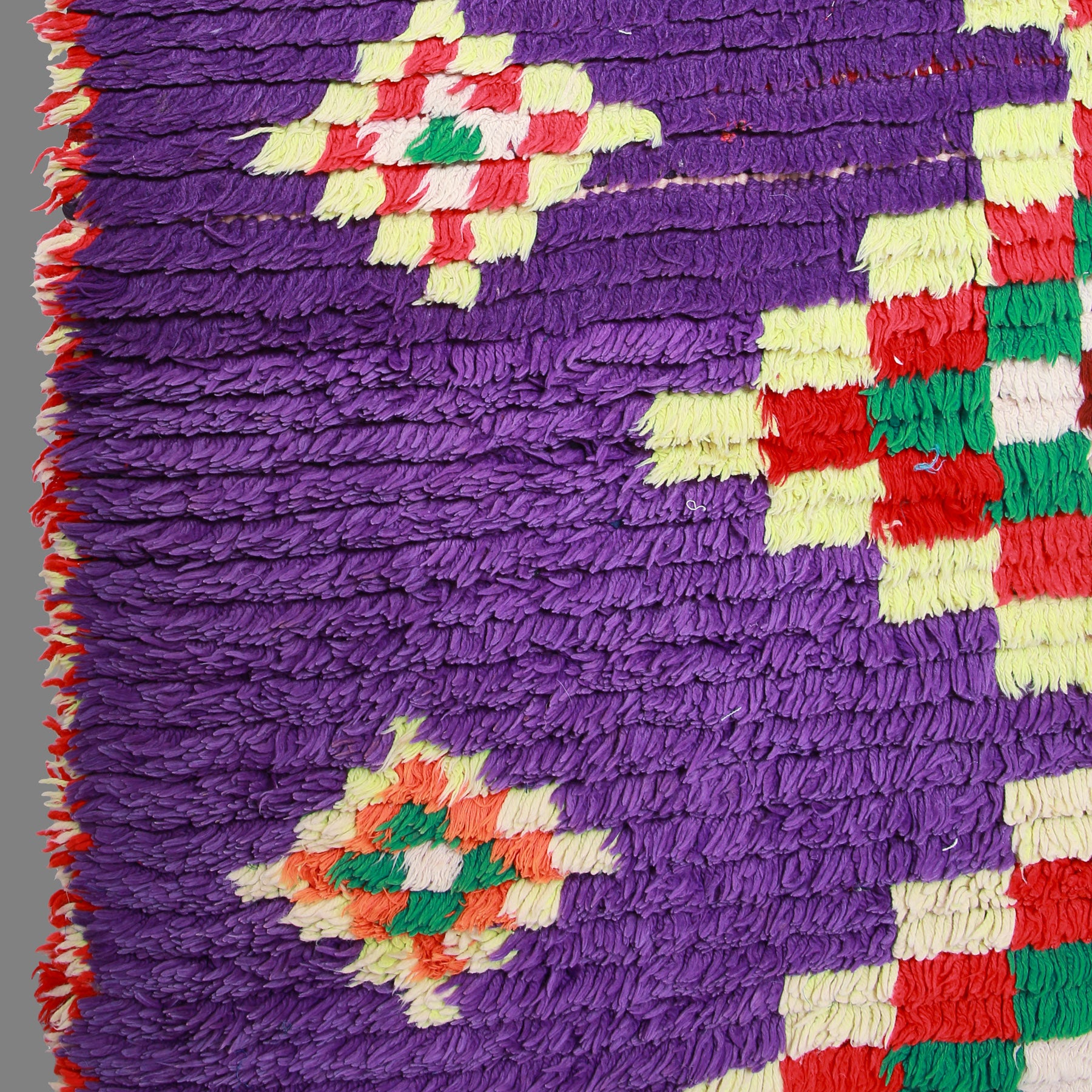 dettaglio della lana viola intrecciata e dei rombi anchessi di lana annodata di un tappeto vintage