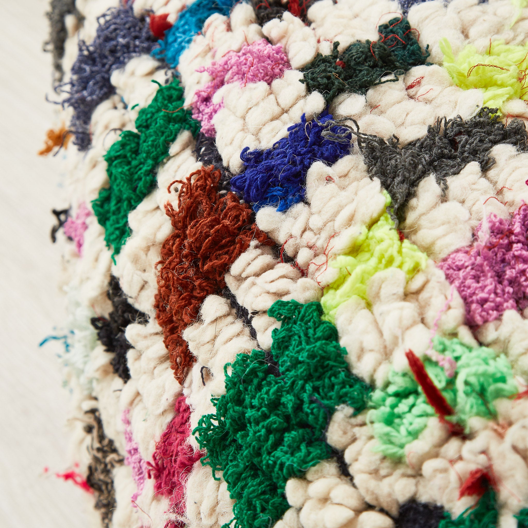 dettaglio di un pouf ricavato da un tappeto vintage, con dettagli di tessuto di diverso materiale e colore