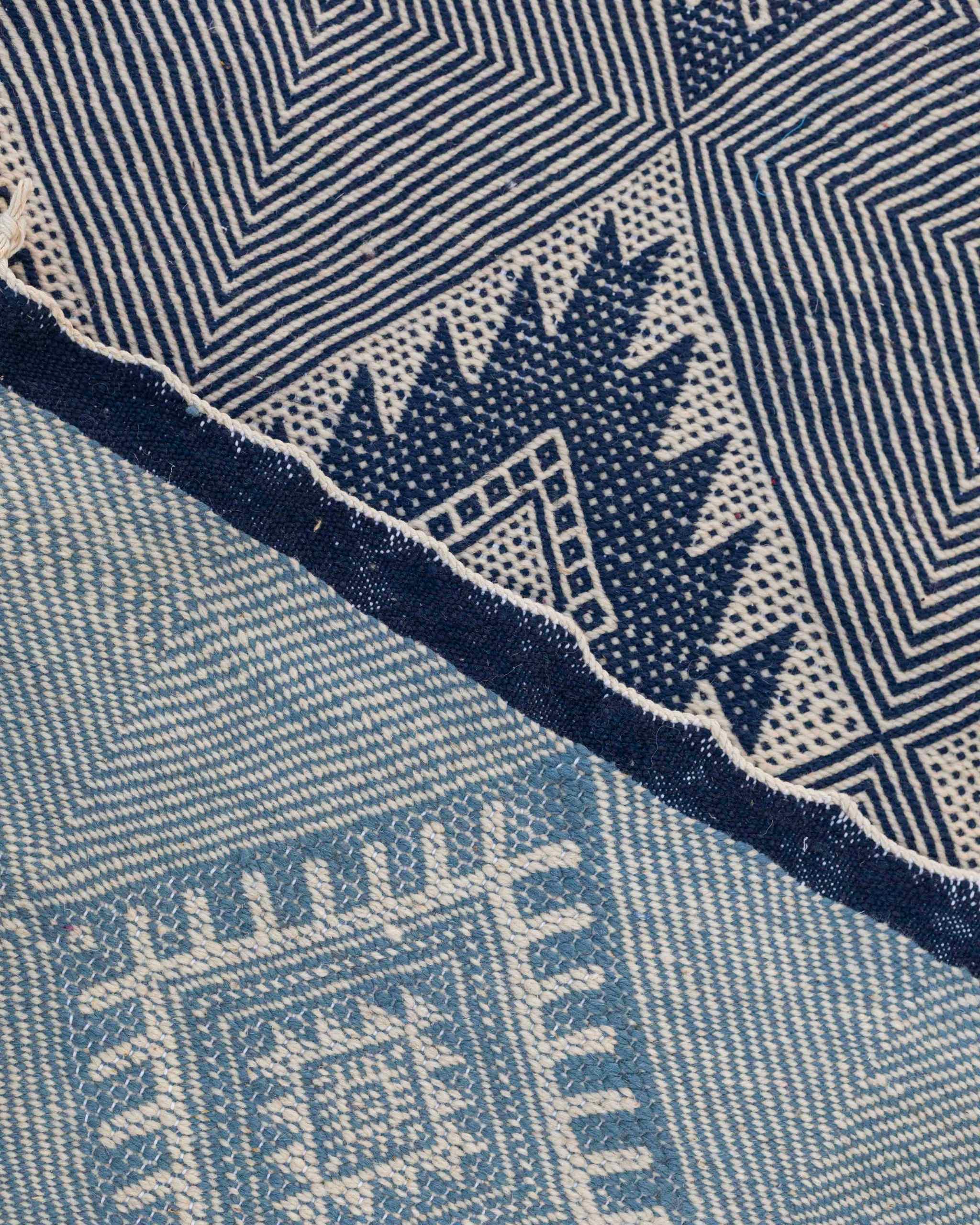 Dettaglio del bordo blu della passatoia Zanafi bianca e azzurra con motivi geometrici tessuti a mano
