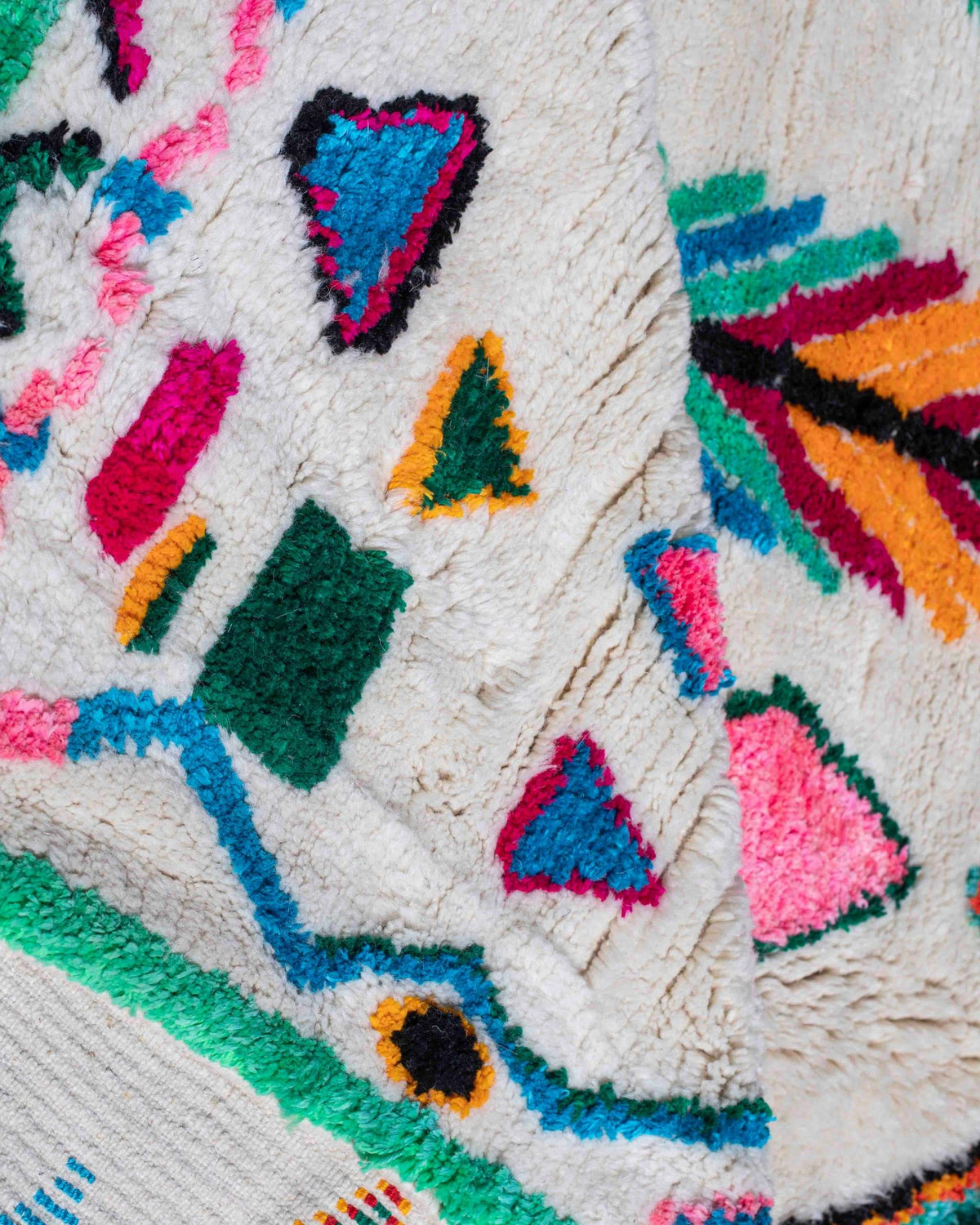Dettaglio di rombi e simboli colorati su fondo bianco del tappeto Azilal in lana e filati misti