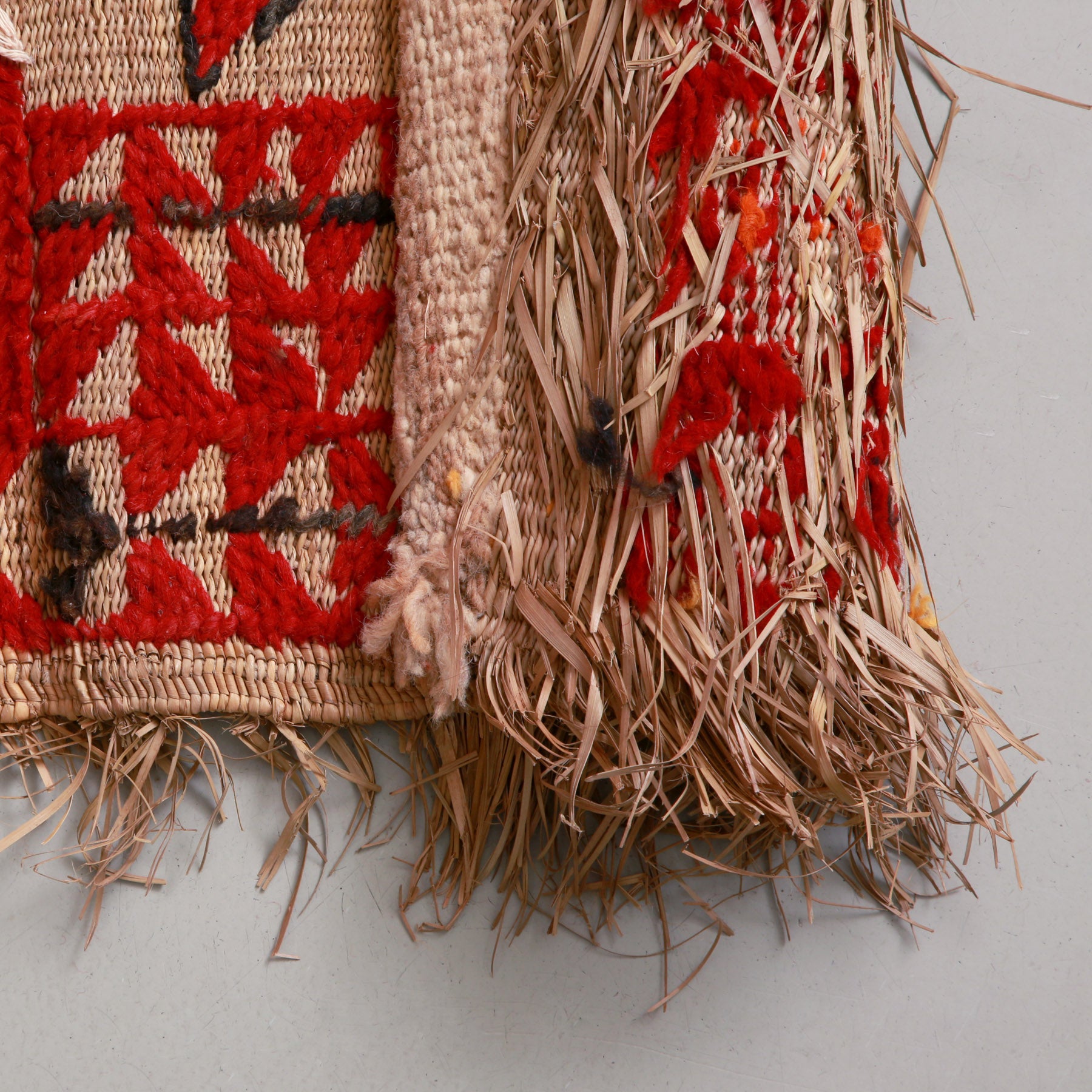 retro di una stuoia in paglia di palma con ricami in lana rossa e nera