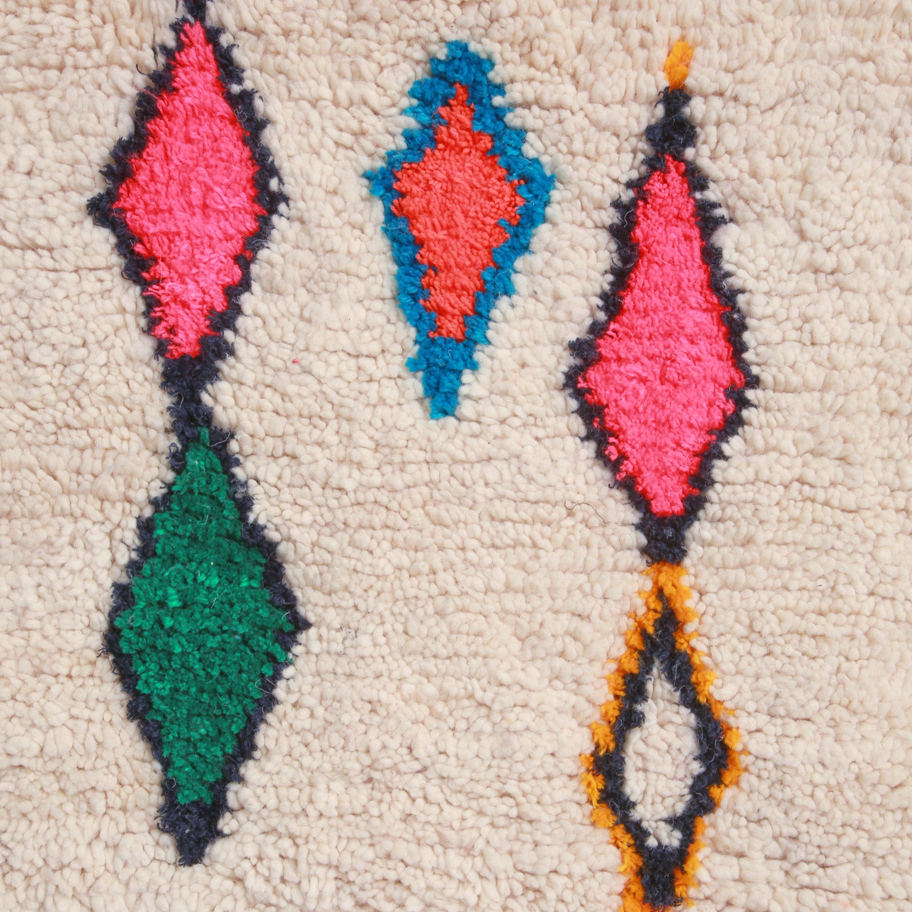 dettaglio dei simboli a forma di rombo con colori sgargianti come il rosa il verde con contorni neri blu e gialli di un tappeto marocchino azilal realizzato a mano