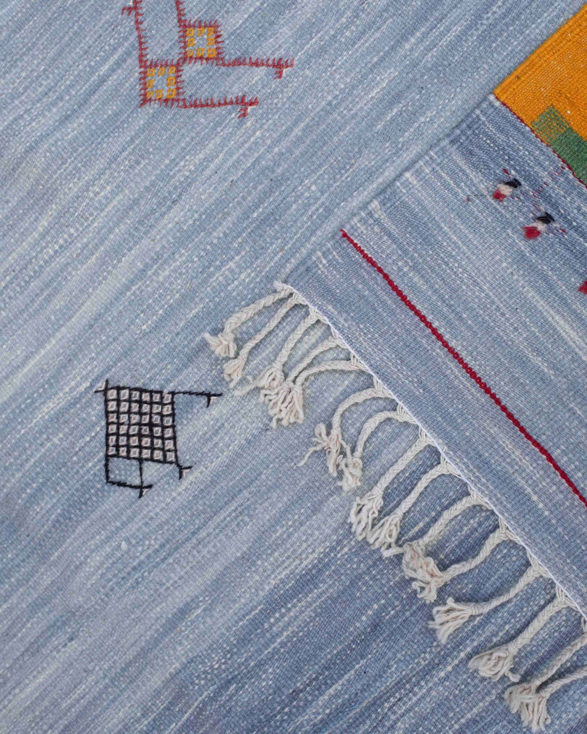 Dettaglio frange e cimosa tappeto Akhnif hanbel/kilim in lana: campo azzurro con simboli amazigh e finitura artigianale