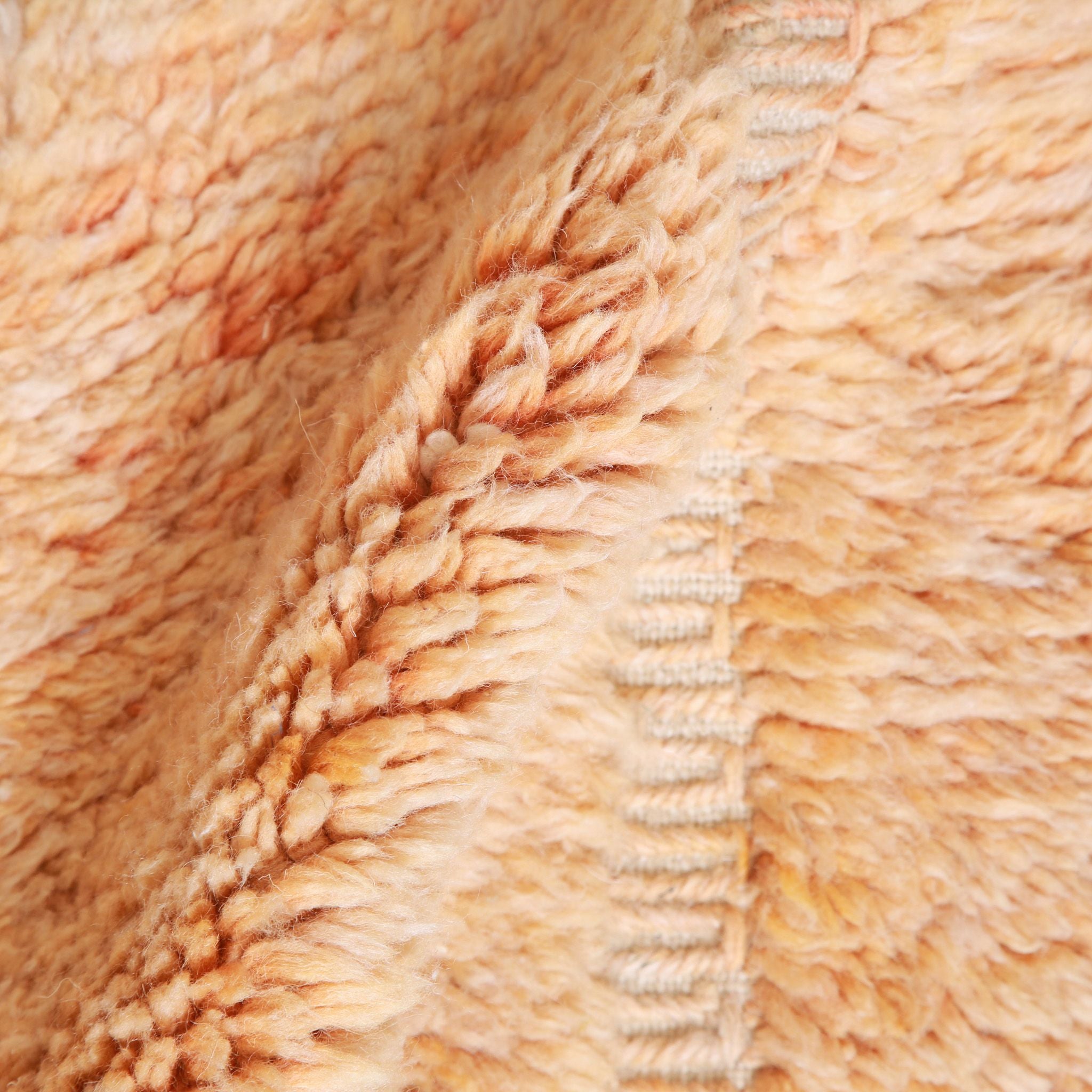 Dettaglio pelo lungo tappeto Beni Ourain artigianale in lana naturale con toni caldi pesca, texture morbida per interni minimalisti e contemporanei