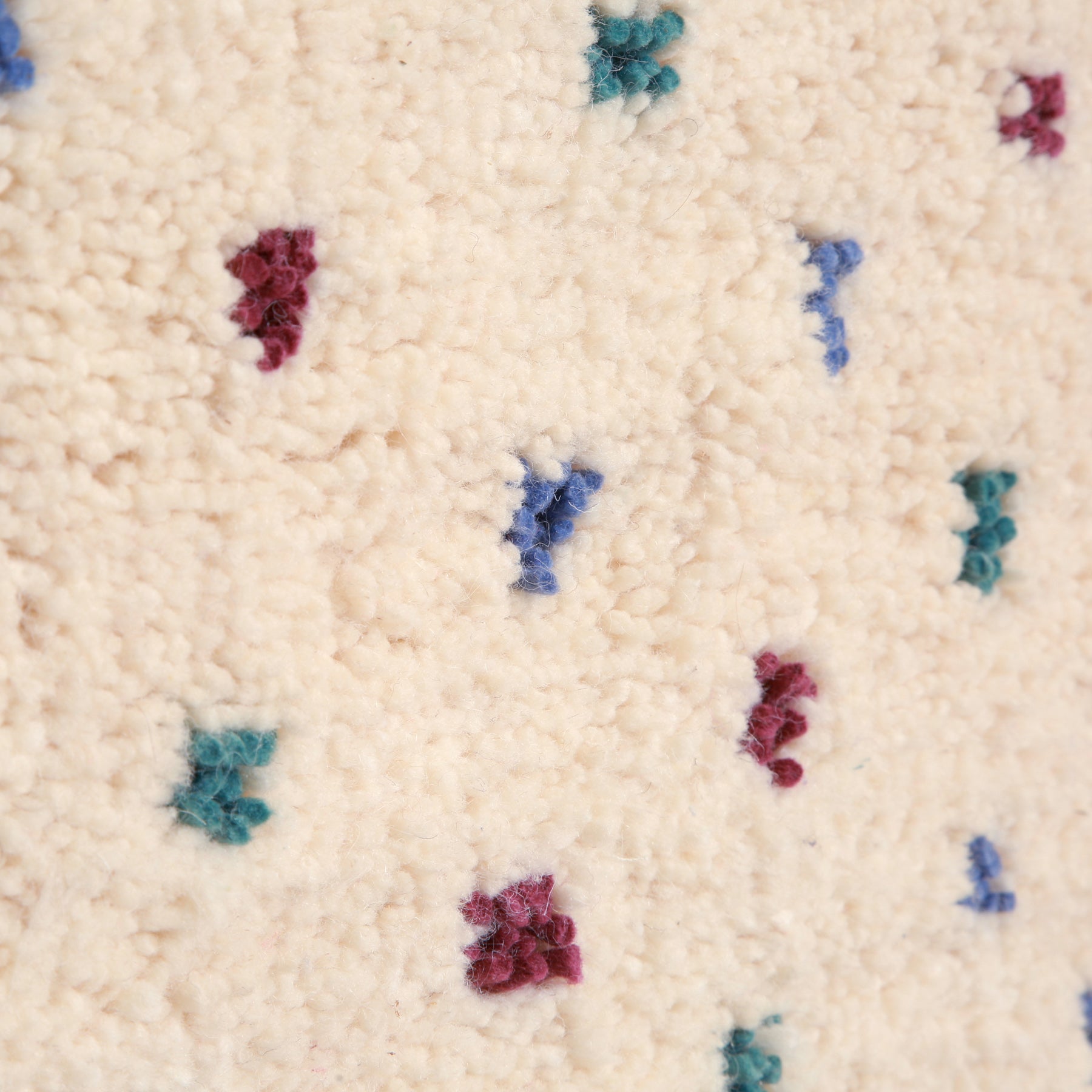 dettaglio della lana avorio e dei poi color pastello di un tappeto