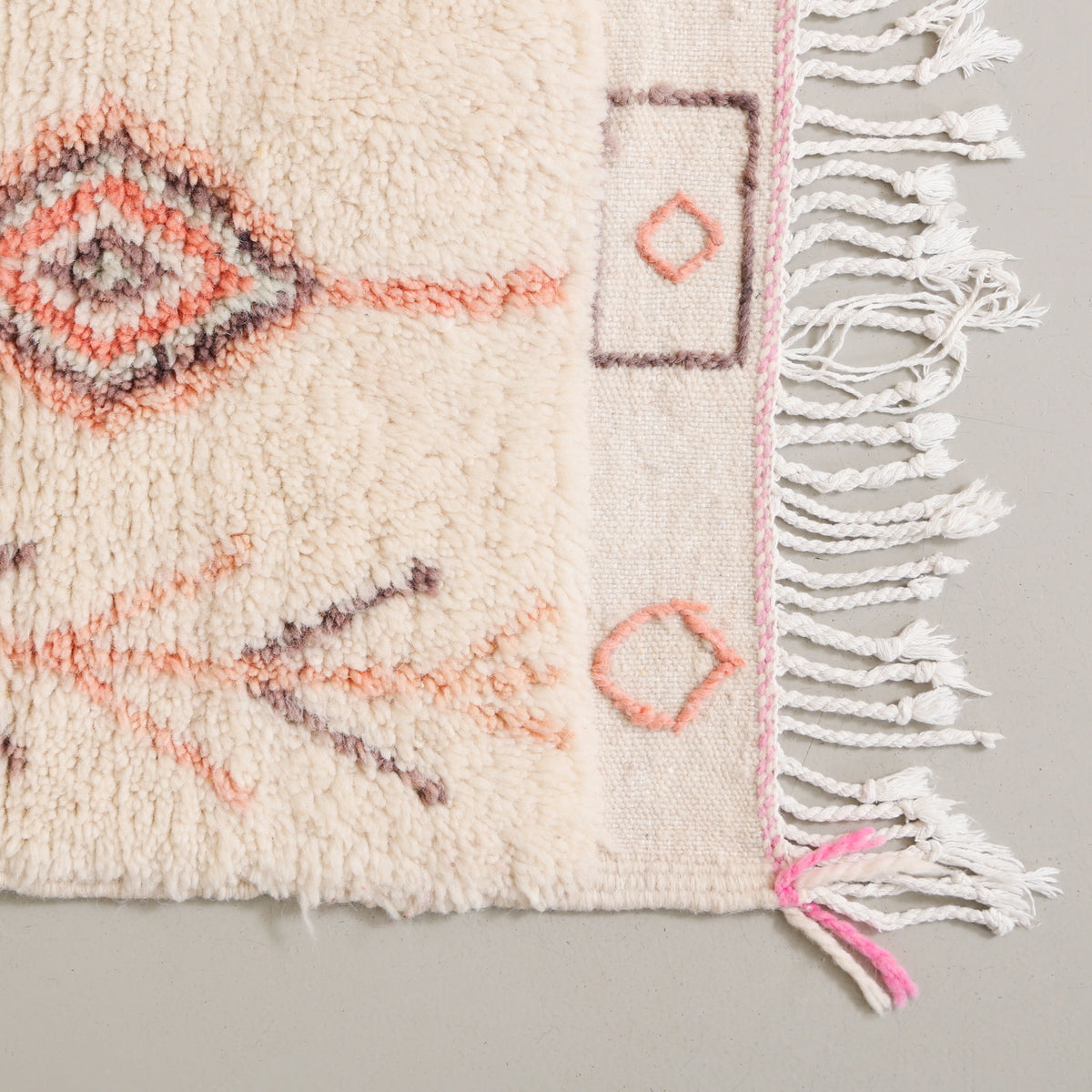 dettaglio dell'angolo e della frangia ricamata di un tappeto realizzato a mano in lana