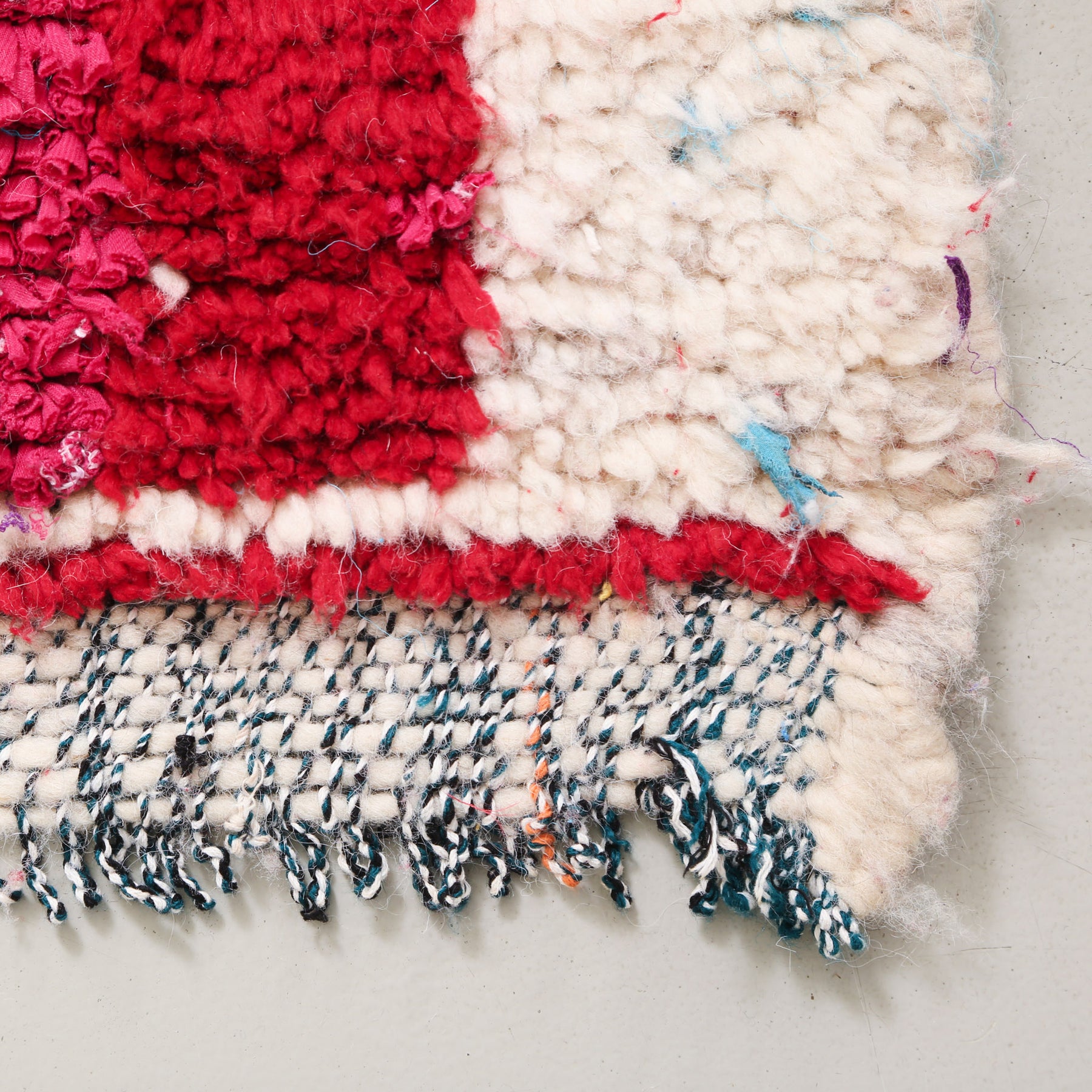 angolo di tappeto con lana bianca e banda rossa in stracci di tessuto