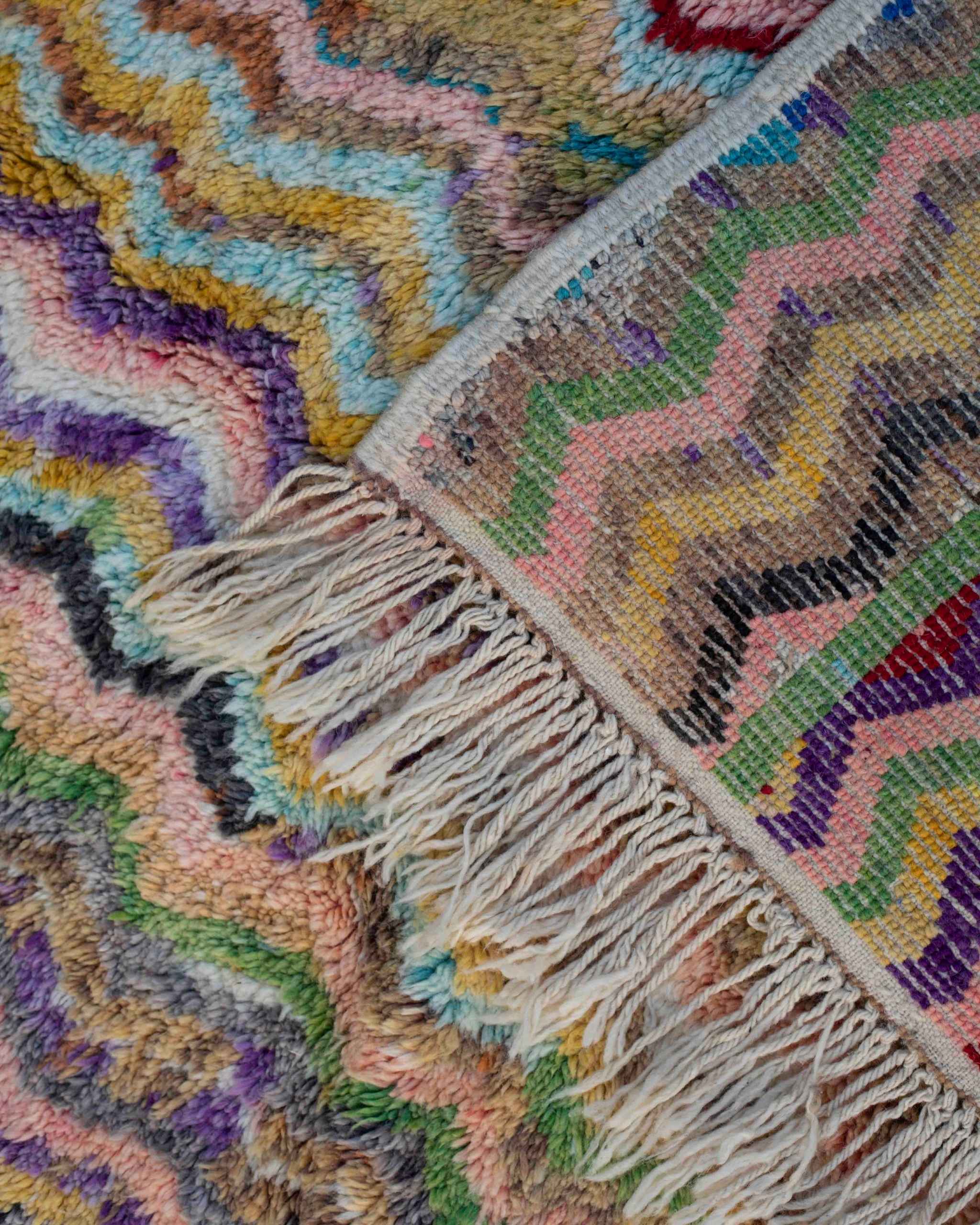 Dettaglio frange e retro tappeto Beni Ourain annodato a mano in lana, trama con motivo chevron multicolor.