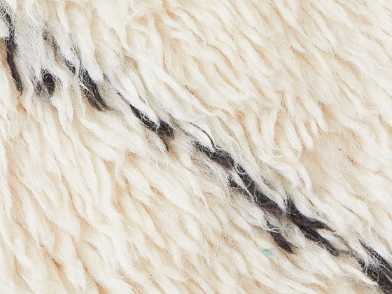 Dettaglio tappeto a pelo lungo con morbido vellobianco con linea nera obliqua centrale 