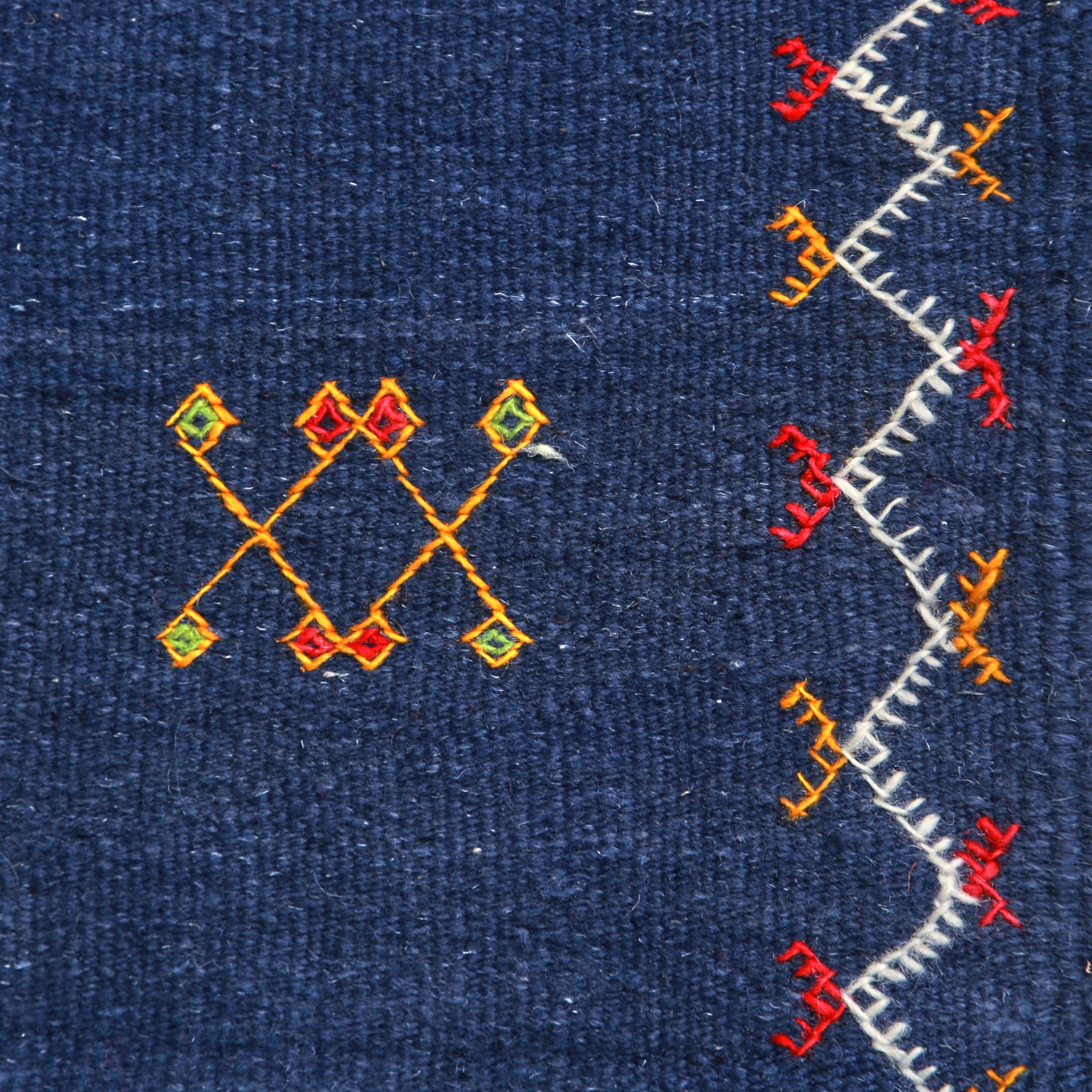 dettaglio di un simbolo amazigh e della cornice ricamata su un tappeto artigianale marocchino a tessitura piatta