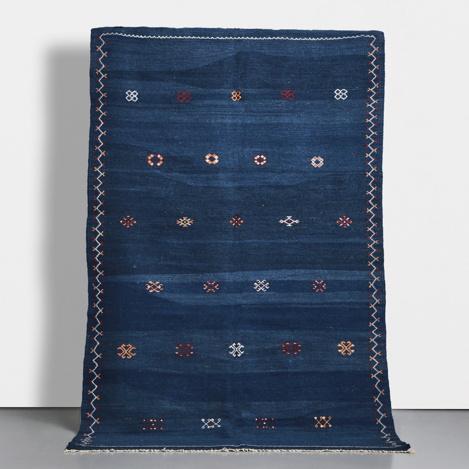 Tappeto marocchino akhnif a tessitura piatta realizzato a mano tessendo lana di varie sfumature di blu e ricamando simboli tradizionali amazigh in vari colori