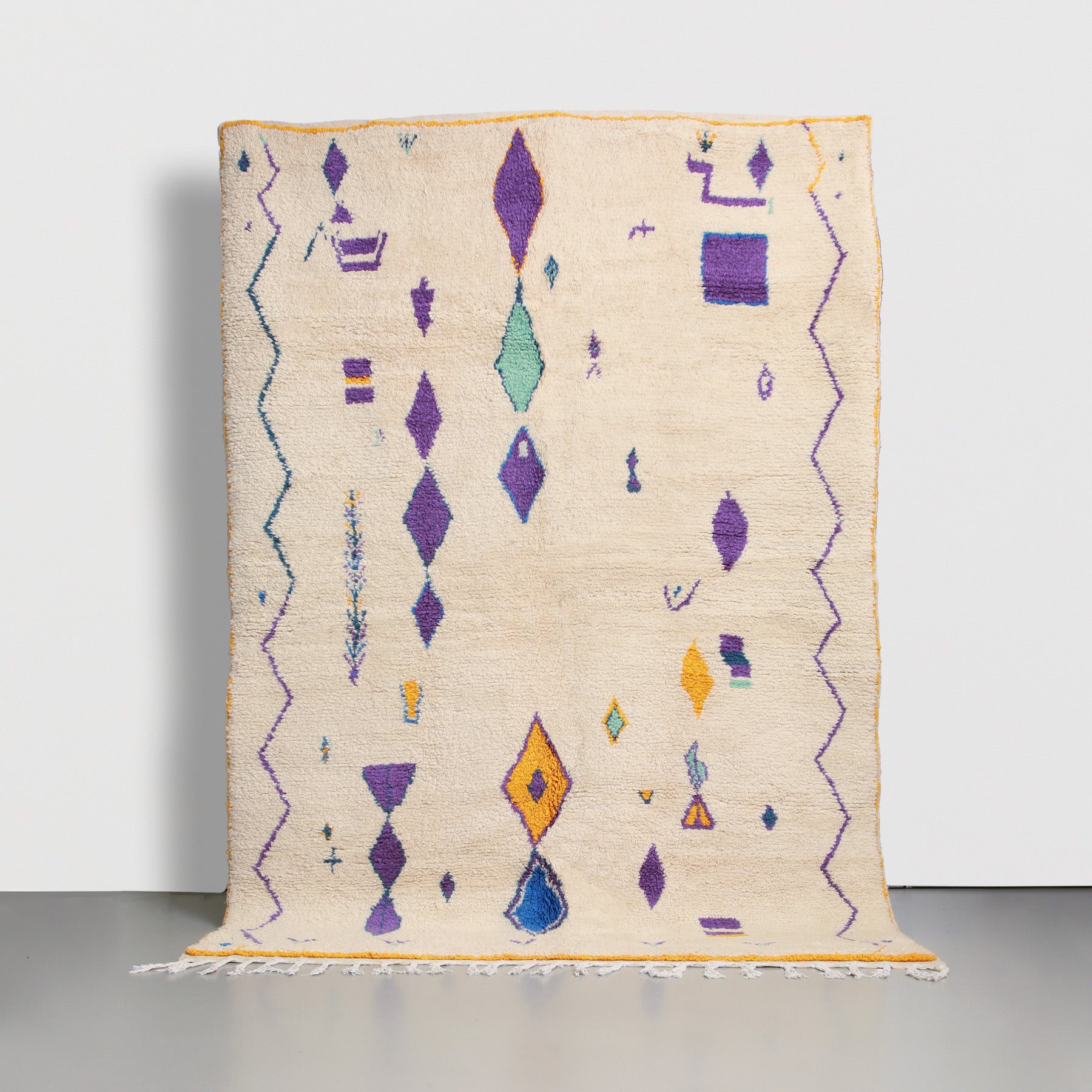 tappeto marocchino azilal realizzato a mano annodando lana color panna con simboli amazigh viola e bordo giallo