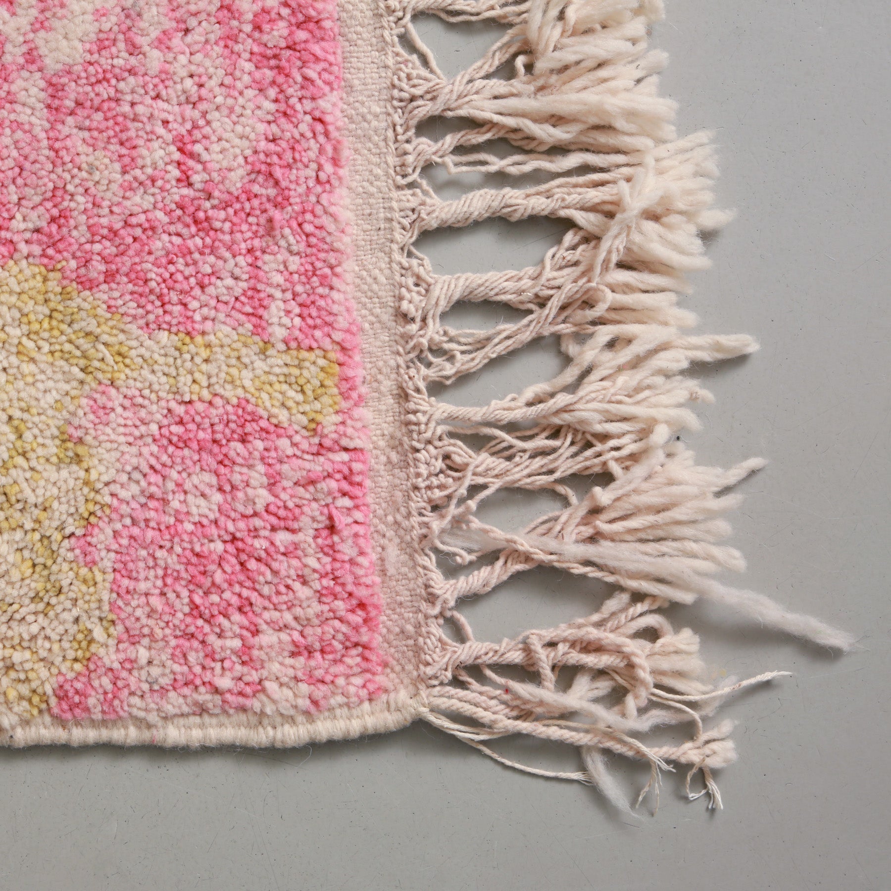 dettaglio della frangia lunga e dei colori sfumati della lana di un tappeto artigianale marocchino beni ourain