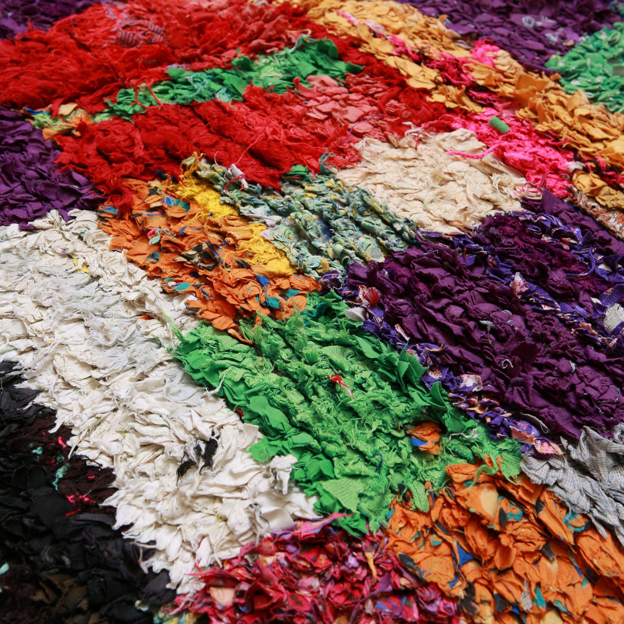 Dettaglio ravvicinato tappeto berbero Boucherouite vintage con texture tridimensionale in tessuti riciclati multicolore, tecnica artigianale Amazigh del Marocco
