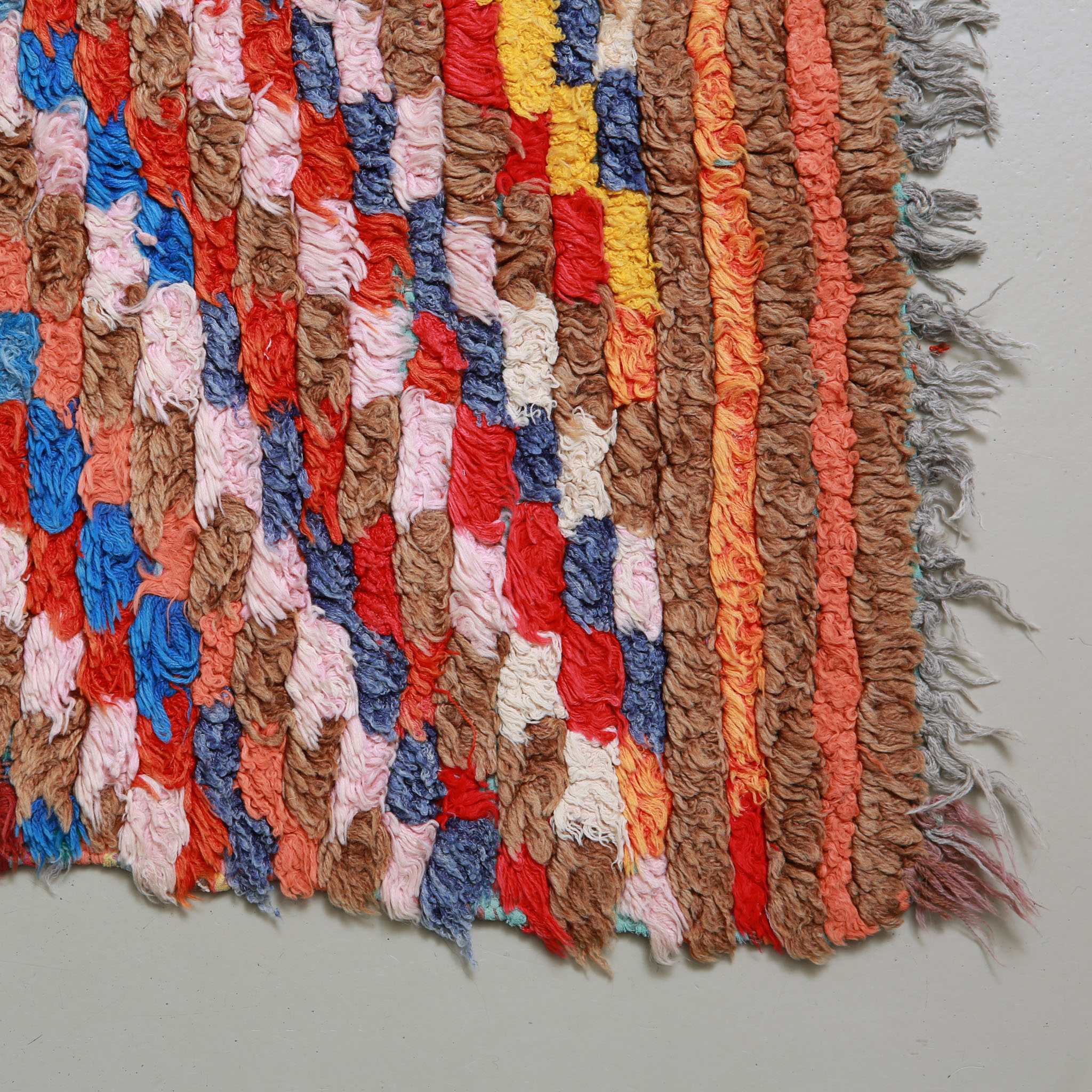 Dettaglio delle frange e bordi di tappeto Boucherouite vintage. Tessitura artigianale a mano con filati riciclati. Perfetto esempio di artigianato marocchino sostenibile. Ideale per arredamento hipster, bohémien o etnico contemporaneo.