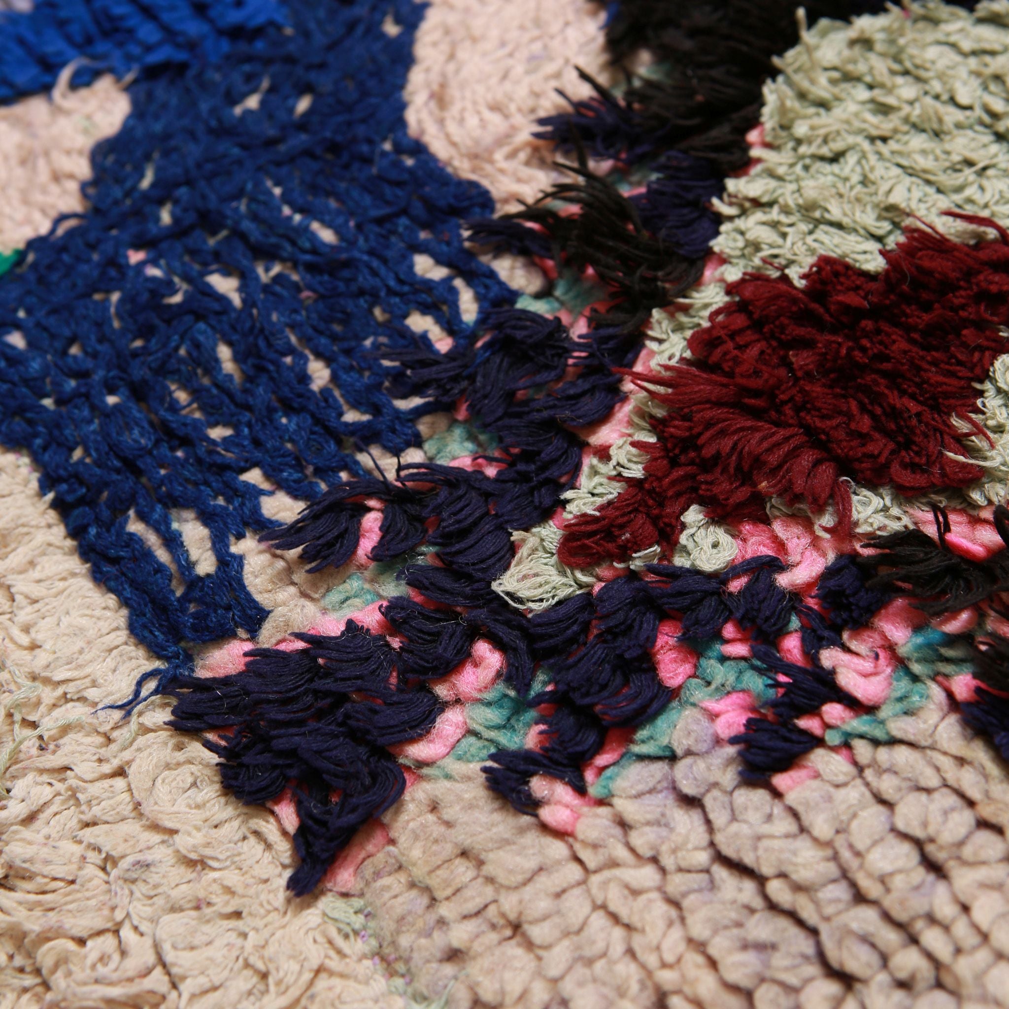 Dettaglio ravvicinato tappeto boucherouite vintage con nodi blu navy, rosso bordeaux e beige naturale su base rosa, mostrando la lavorazione artigianale marocchina con lana e filati