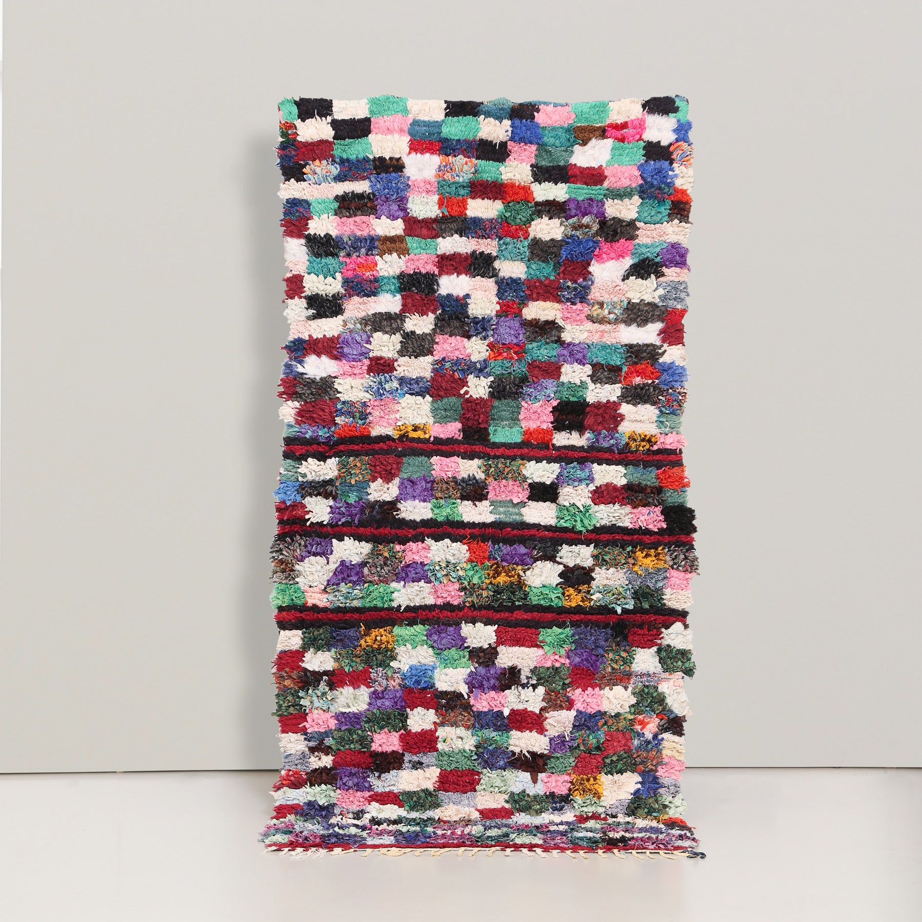 tappeto boucherouite vintage realizzato con stracci di tessuto annodati che formano dei quadrati dai colori  pastello, con tre bande orizzontali nere e rosse