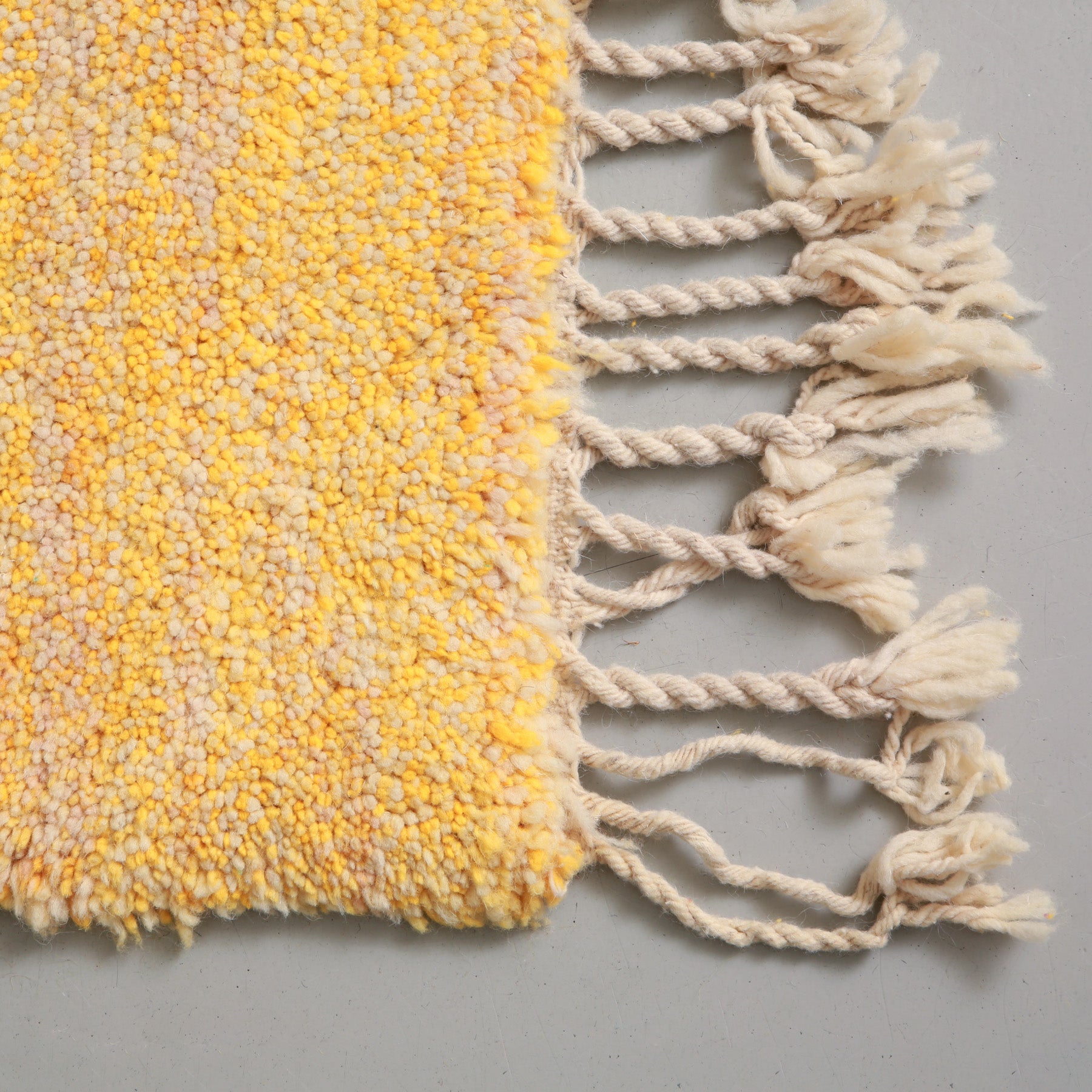 dettaglio dell'angolo e della frangia lunga  e della lana dalle molteplici sfumature di giallo di un tappeto beni ourain realizzato a mano