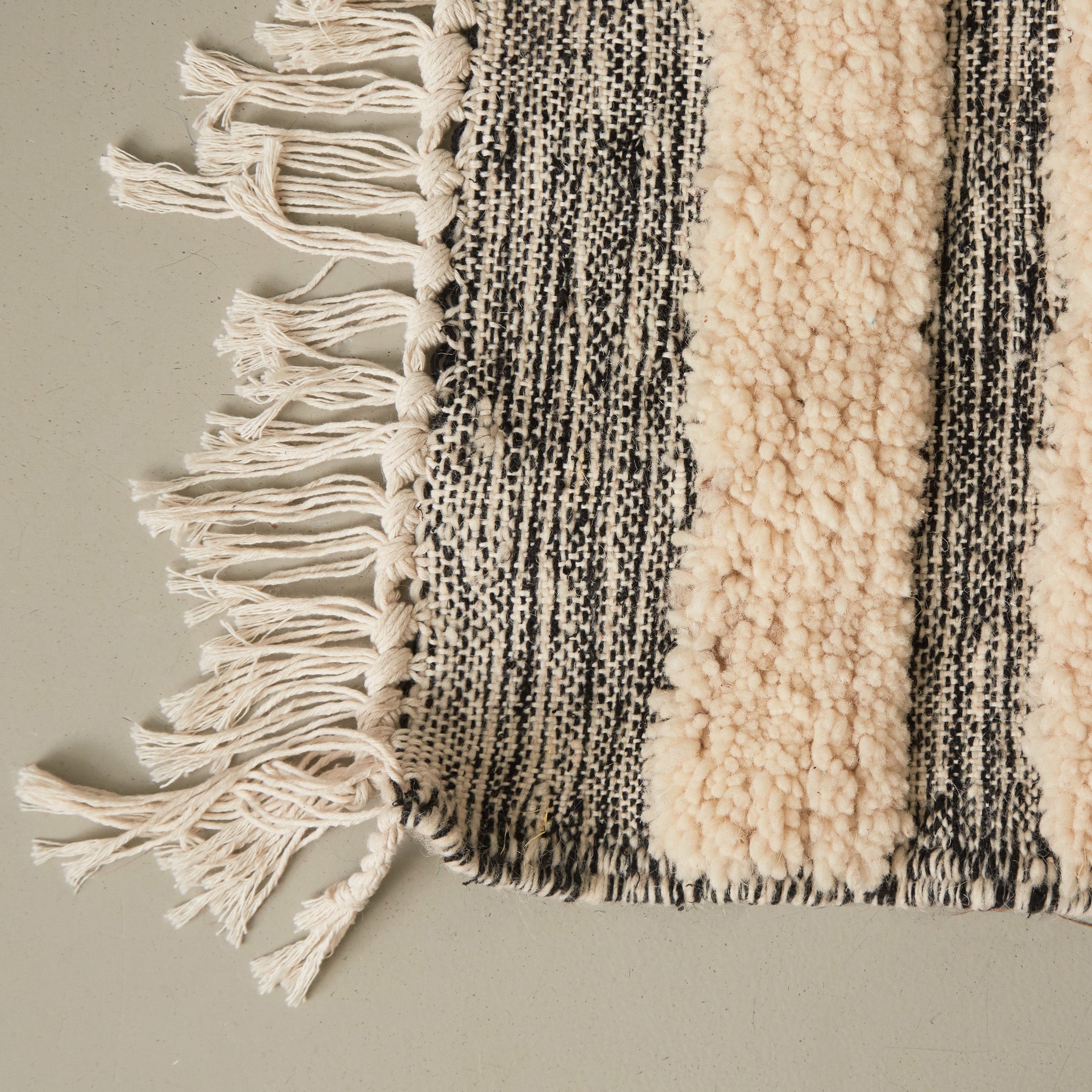 dettaglio della frangia e della lavorazione di un tappeto passatoia boujaad realizzato a mano con bande di lana bianca annodata e bande grigie tessute