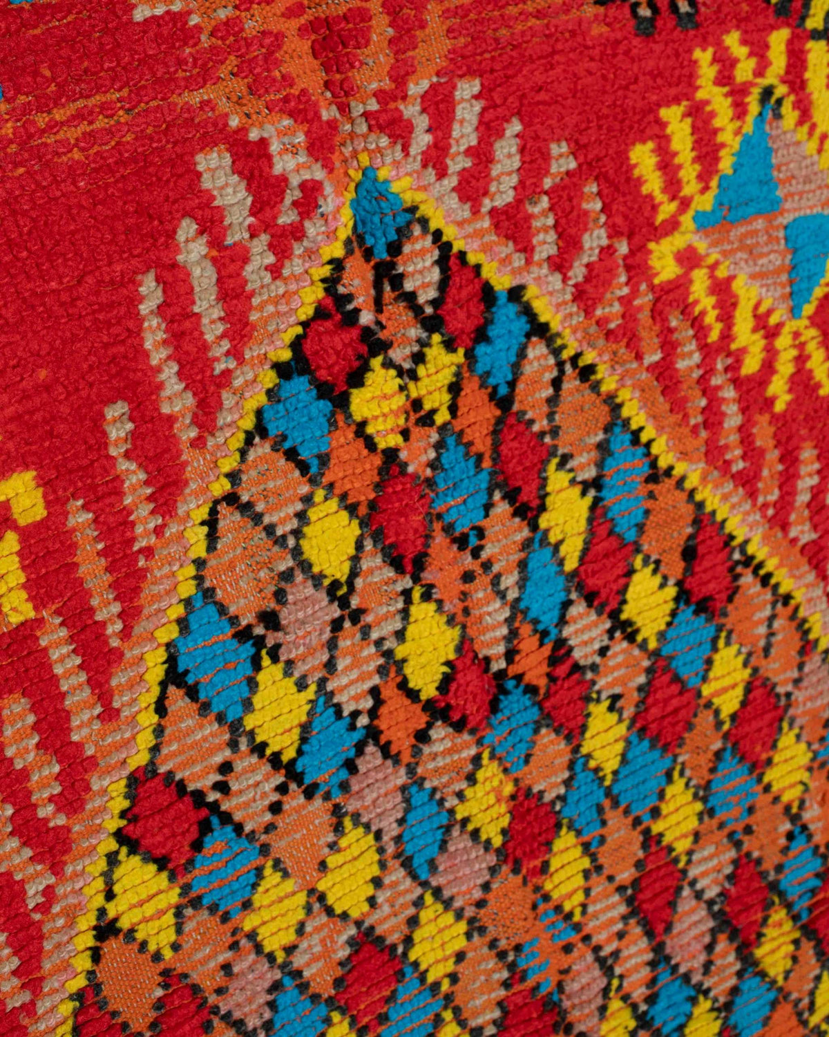 Dettaglio del medaglione centrale a rombi multicolore su fondo rosso del tappeto vintage marocchino