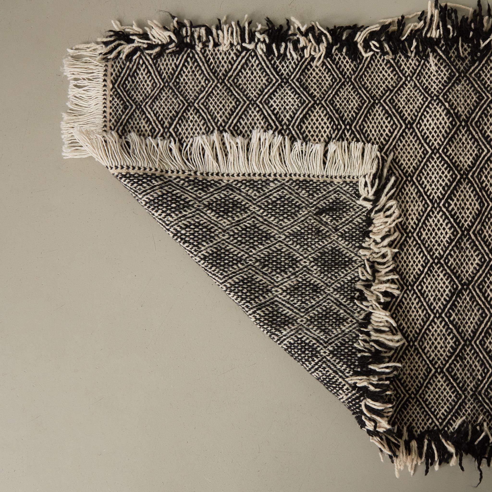 dettaglio del retro di un tappeto zanafi passatioa stile kilim realizzato intrecciando lana bianca e nera