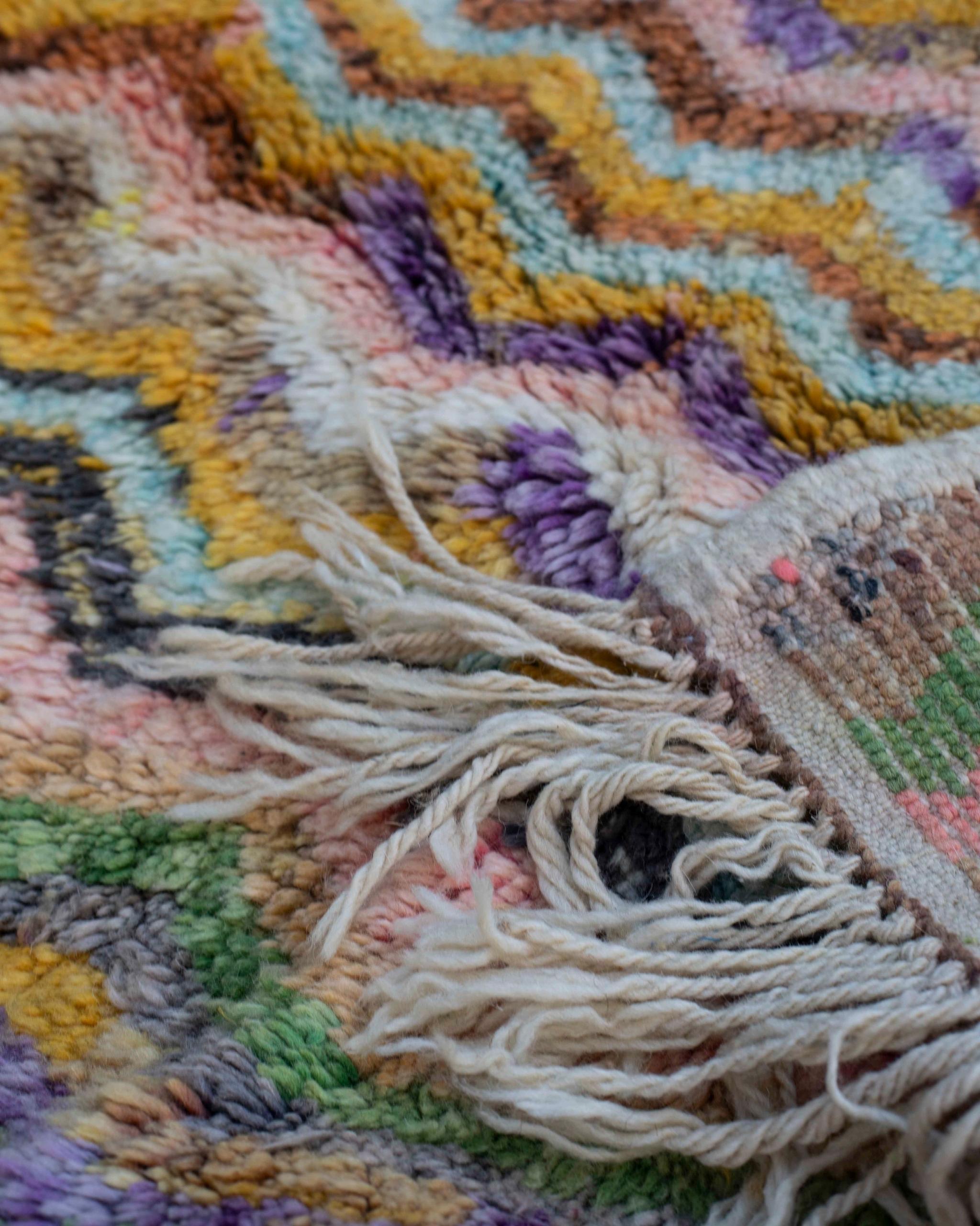 Dettaglio retro e frange del tappeto Beni Ourain a pelo lungo: motivo chevron multicolor e finitura artigianale