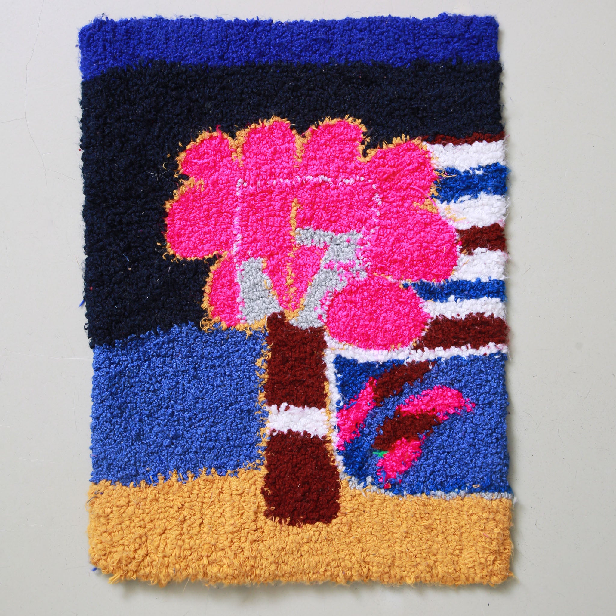 tappeto zindekh realizzato a mano con la tecnica del punch needle su un sacchetto di plastica. il disegno rappresenta un albero astratto con chioma rosa e su fondo blu e nero