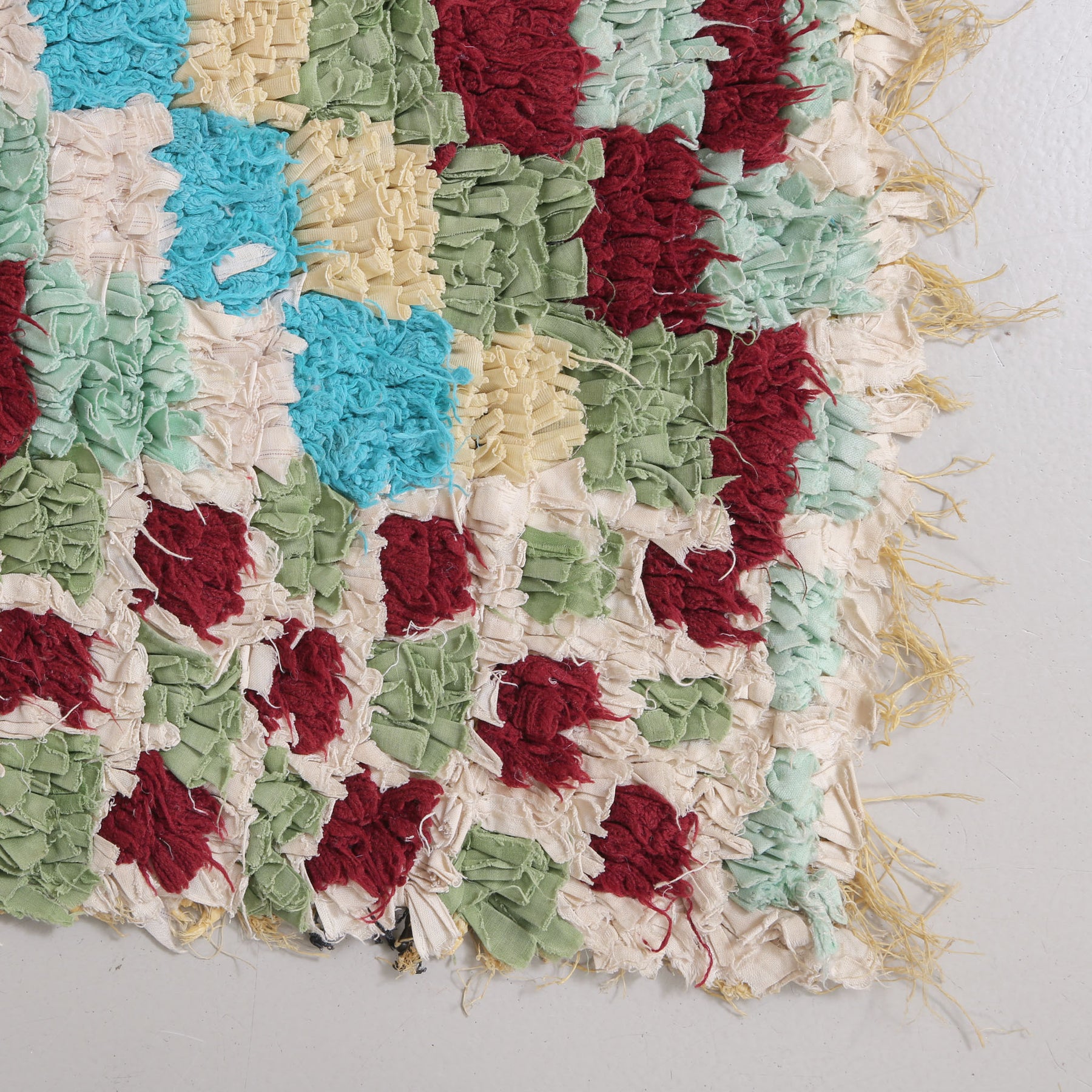 angolo di tappeto zyndech con tessuti di diversi colori che formano dei quadrati annodati su un sacco di plastica