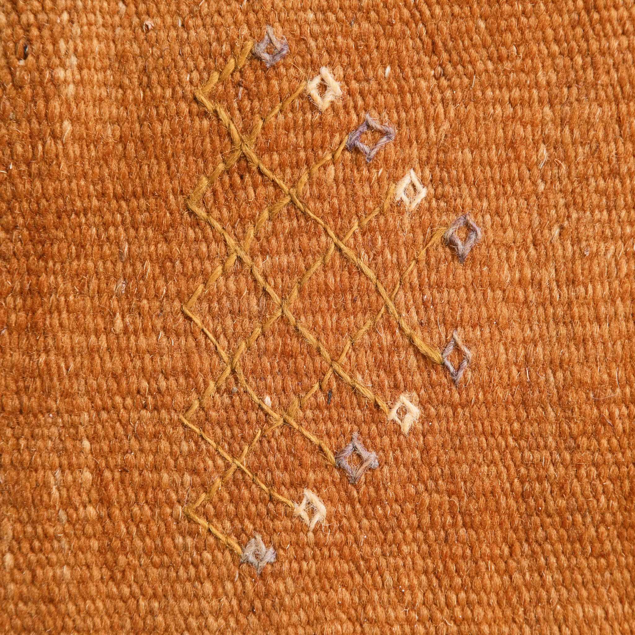Detailed view of Taznakht Akhnif flat-weave pattern showing traditional Berber geometric designs with diamond and cross motifs in orange, blue and cream colors on handwoven Moroccan kilim